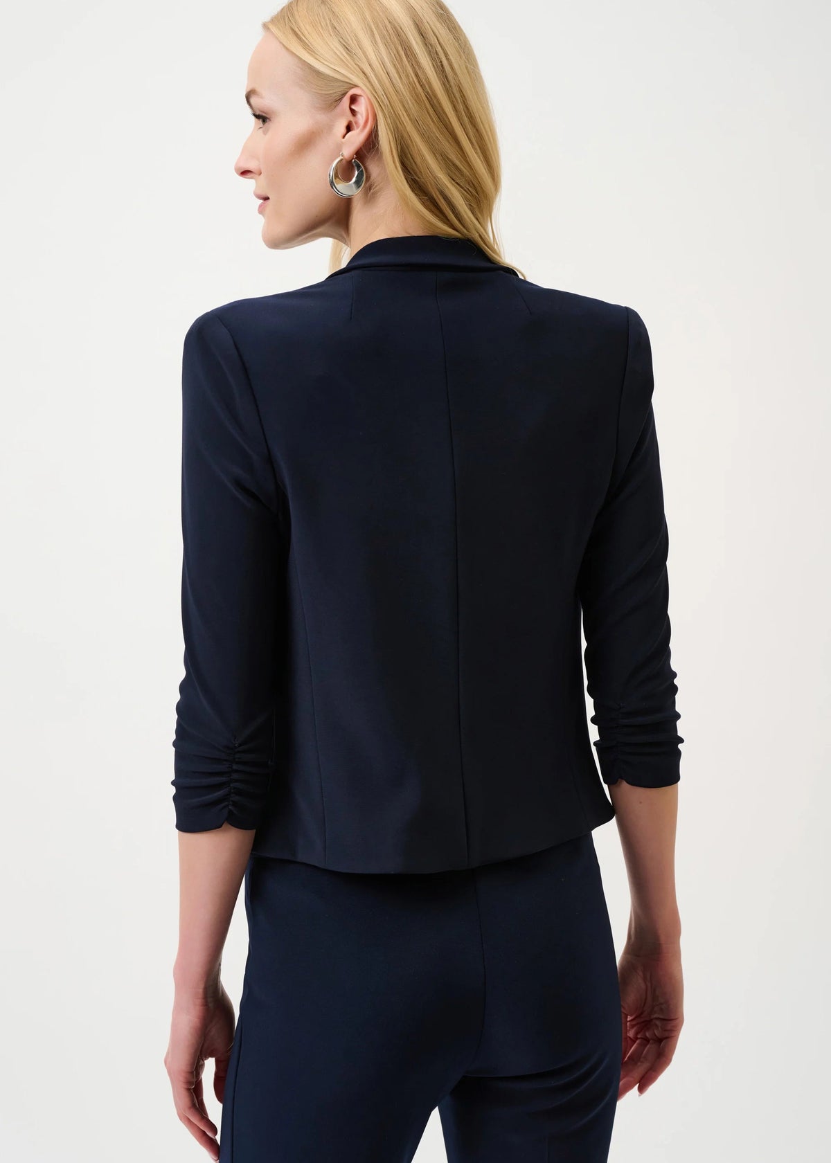 Woman wearing a navy blue blazer and pants on a white background