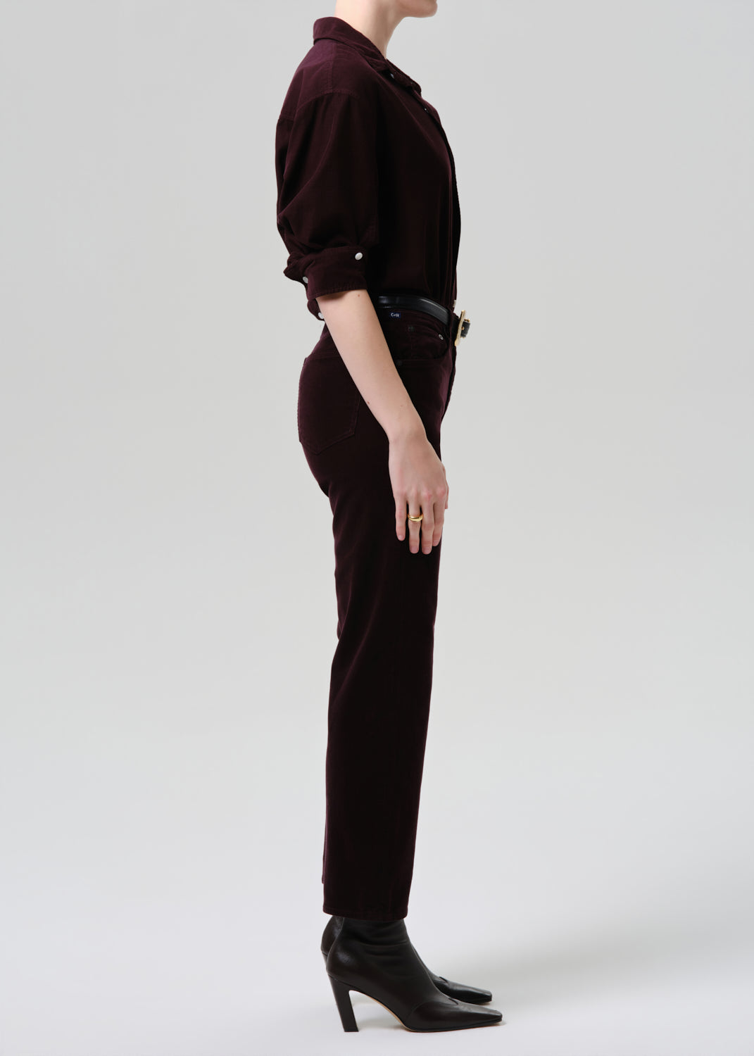 Person wearing a dark brown outfit with high heels on a white background