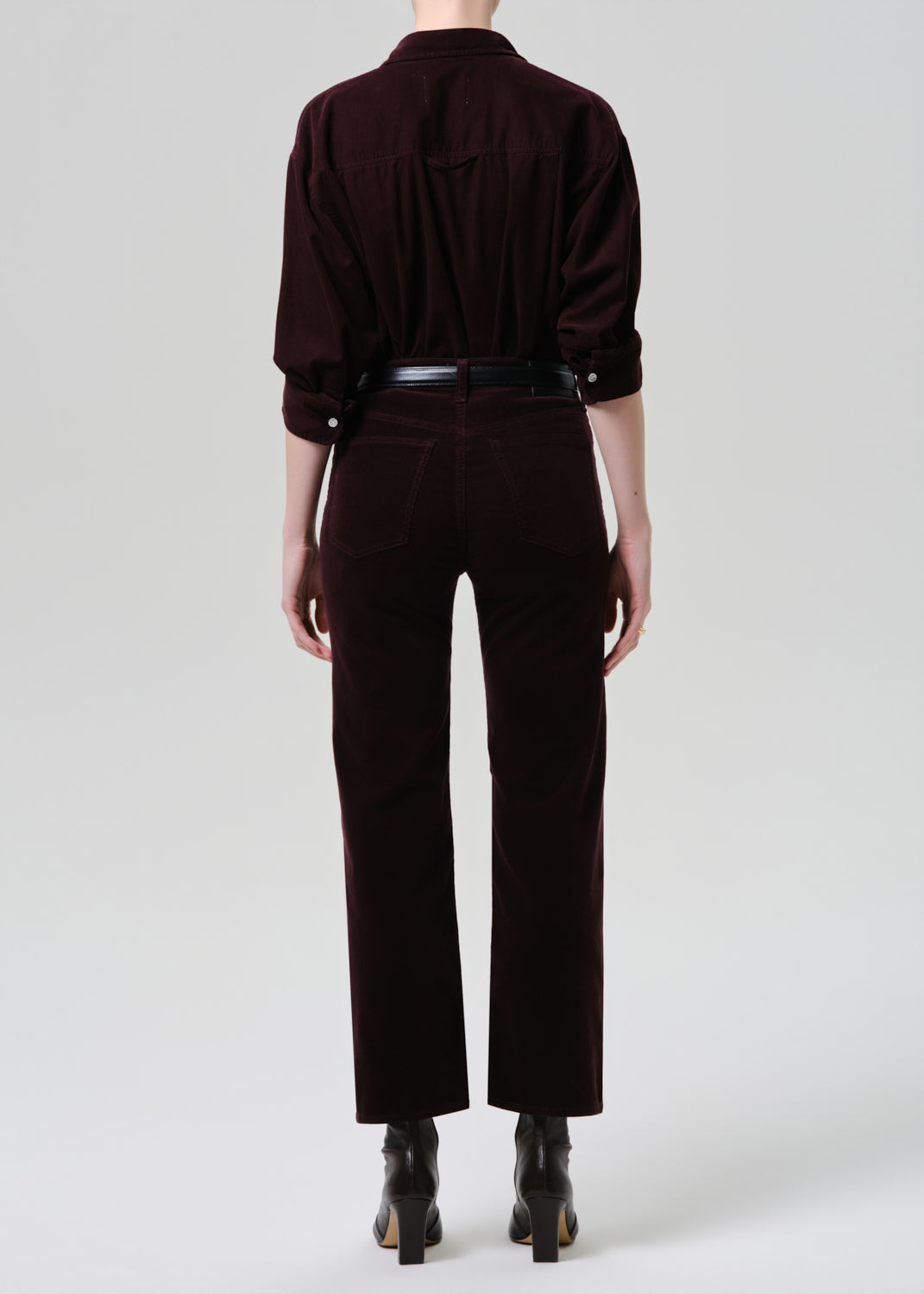 Person wearing a dark brown outfit with a shirt and pants on a white background