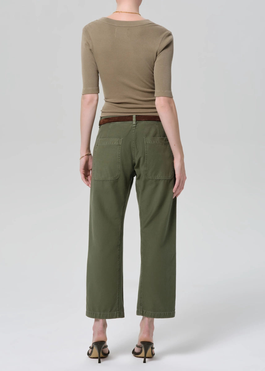 Person wearing a green top and olive green pants on a white background