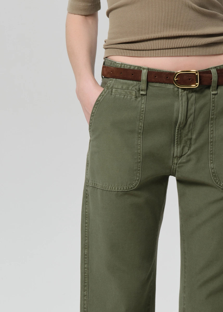 Person wearing green pants with a brown belt on a light gray background
