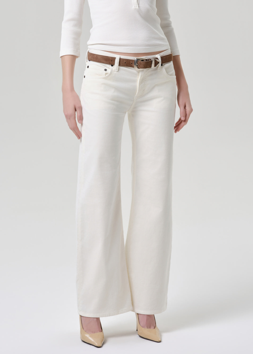 Person wearing white pants with a brown belt on a plain background