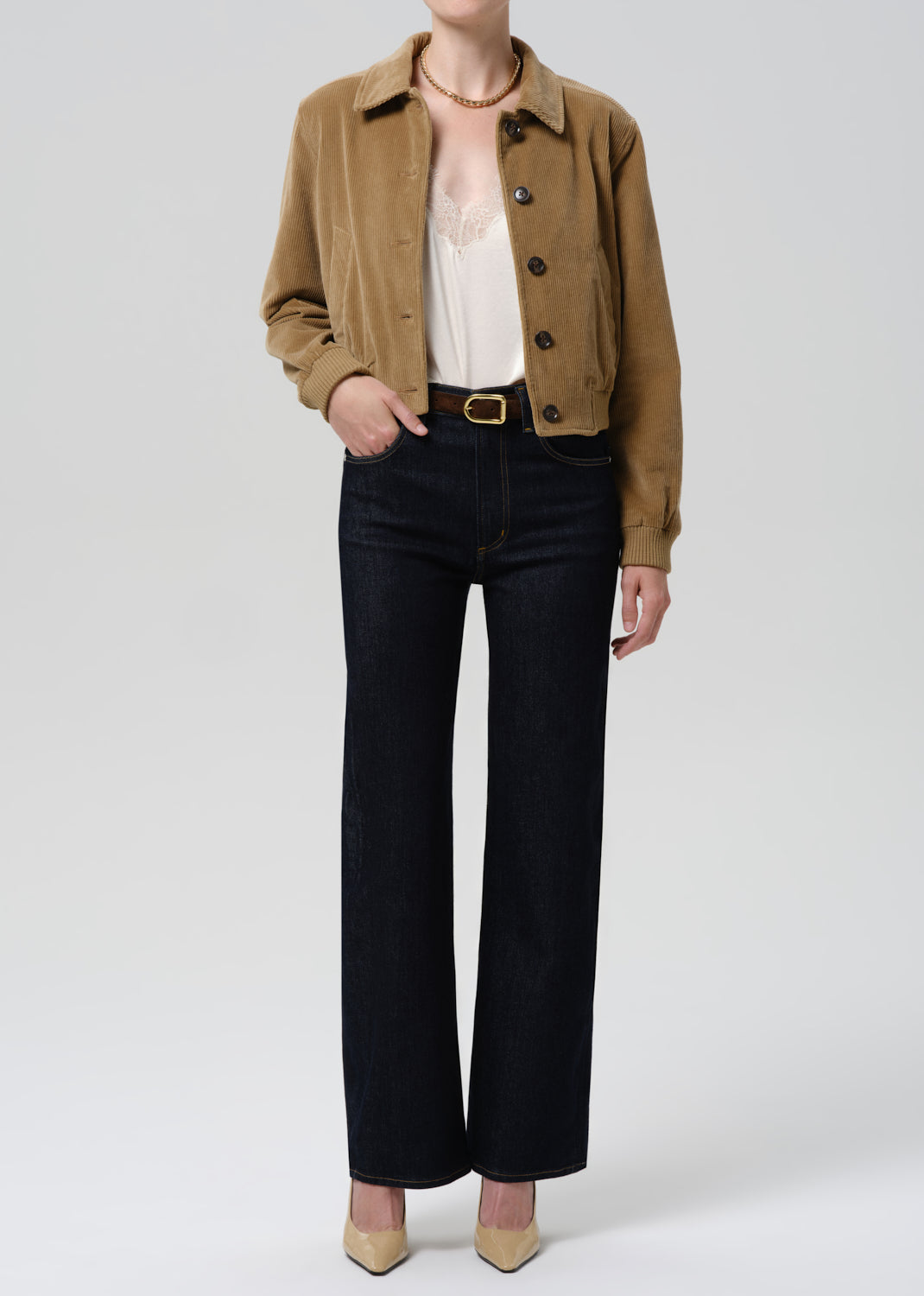 Person wearing a brown jacket and black pants on a white background