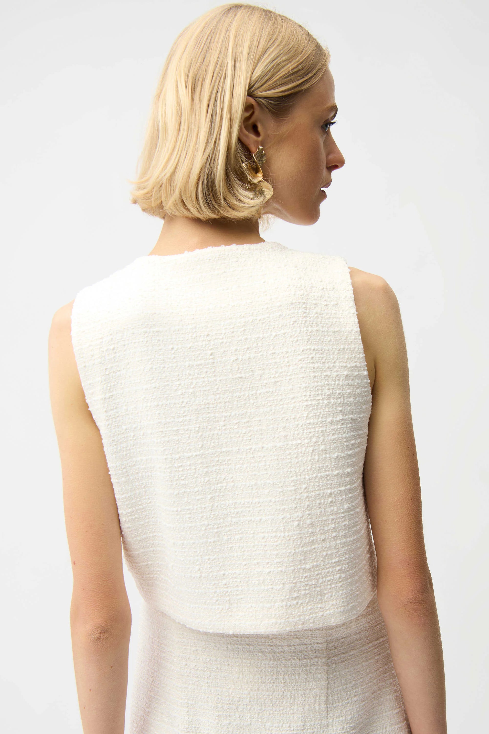 Woman wearing a textured white sleeveless top against a plain background