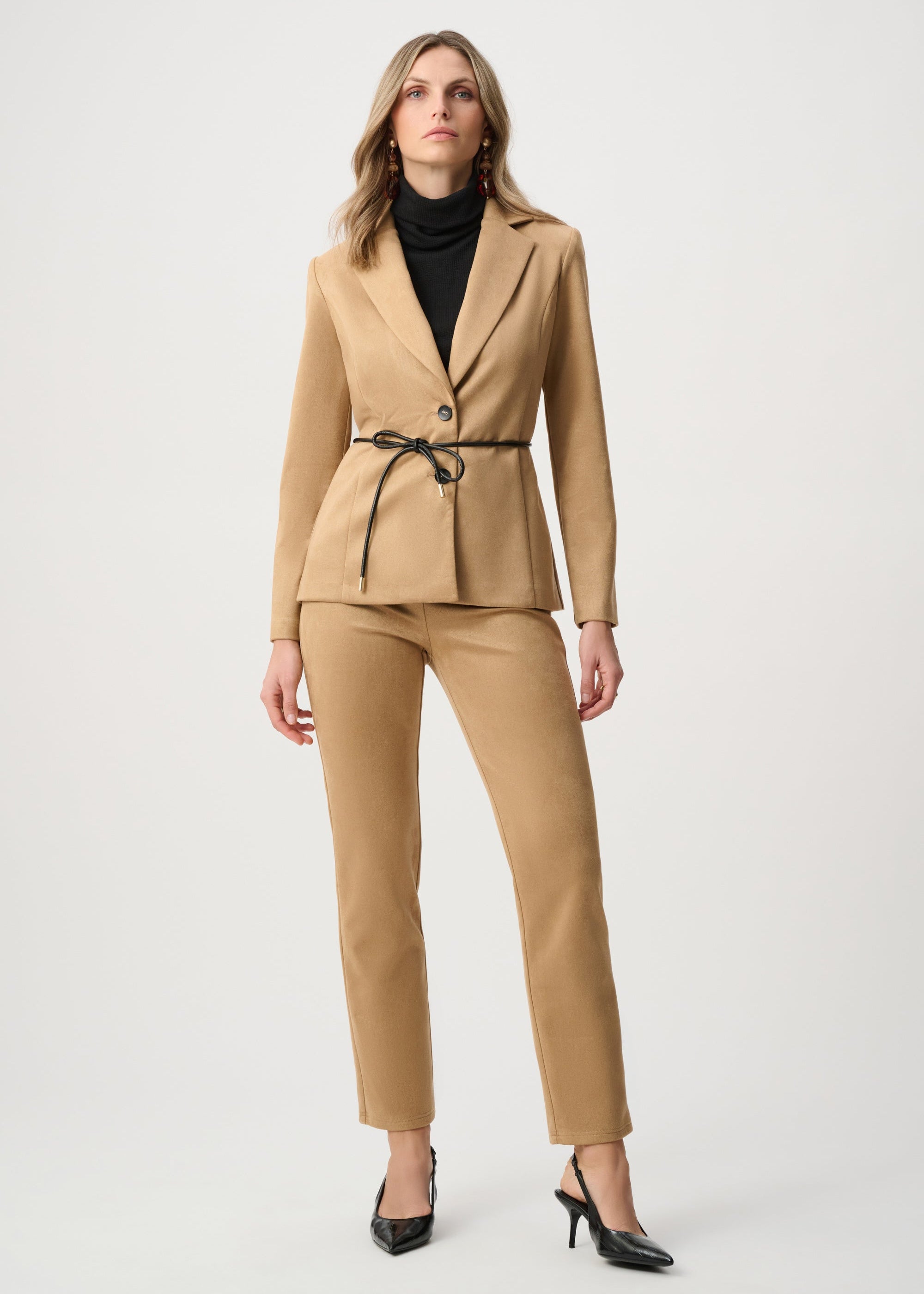 Woman wearing a beige suit with a black top on a white background