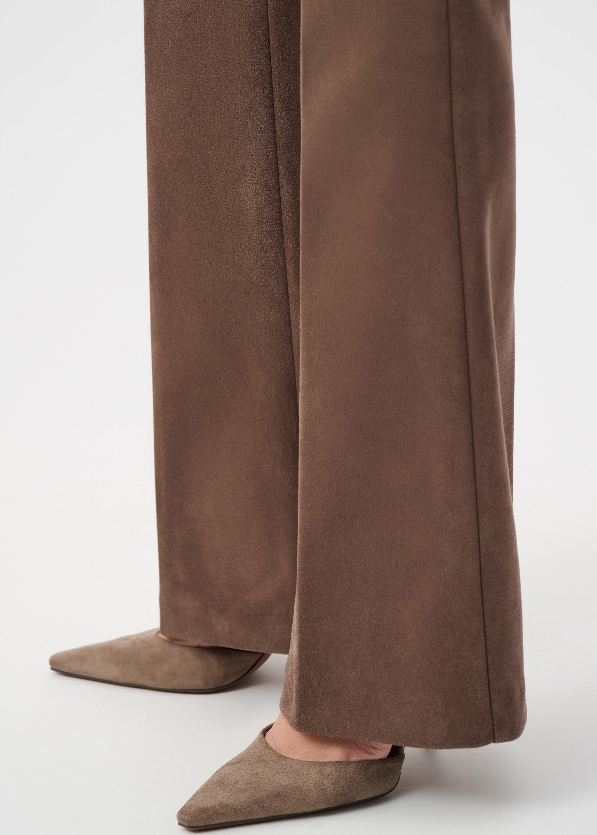 Brown suede pants worn with matching shoes on a white background