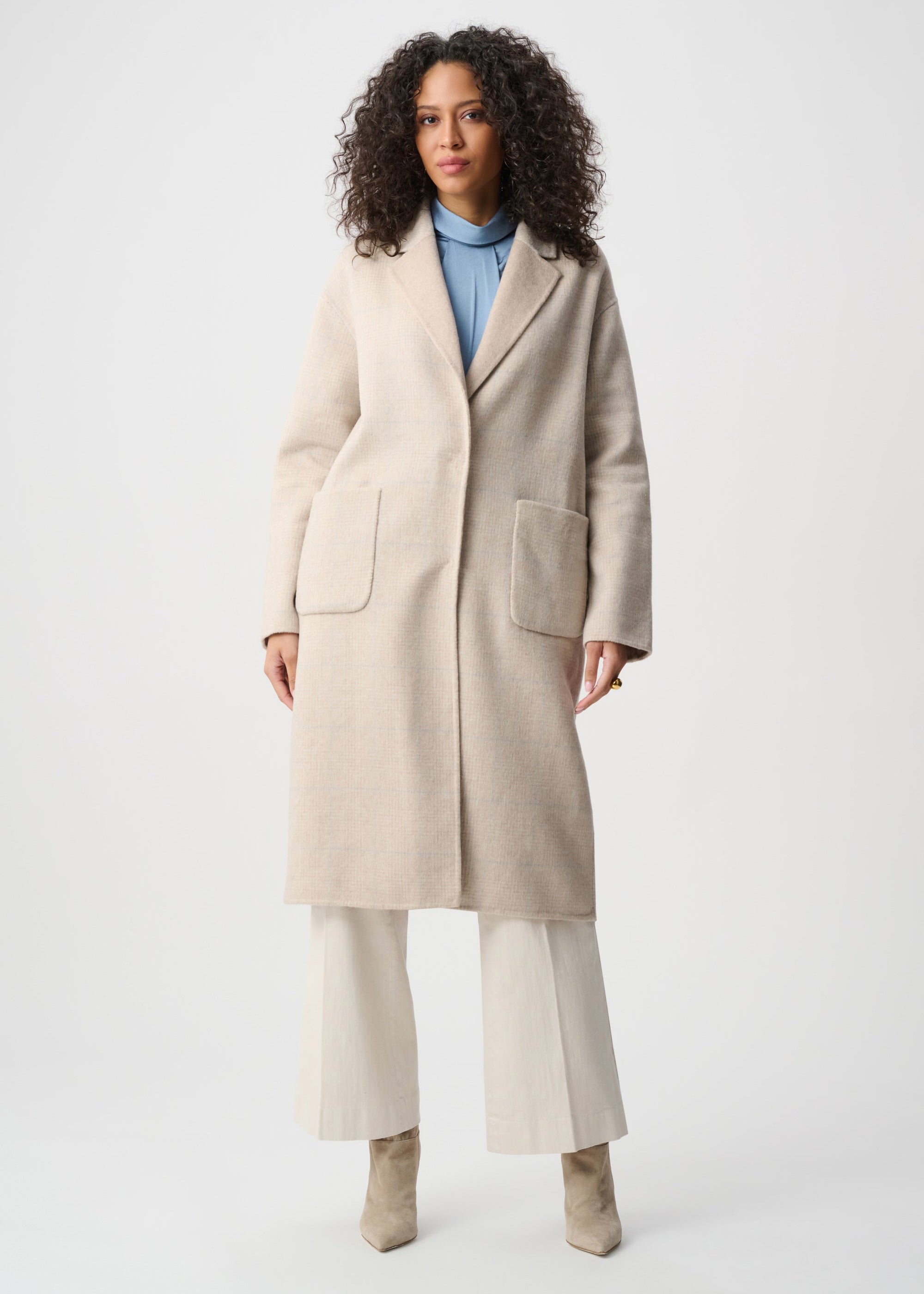 Woman wearing a beige coat on a white background