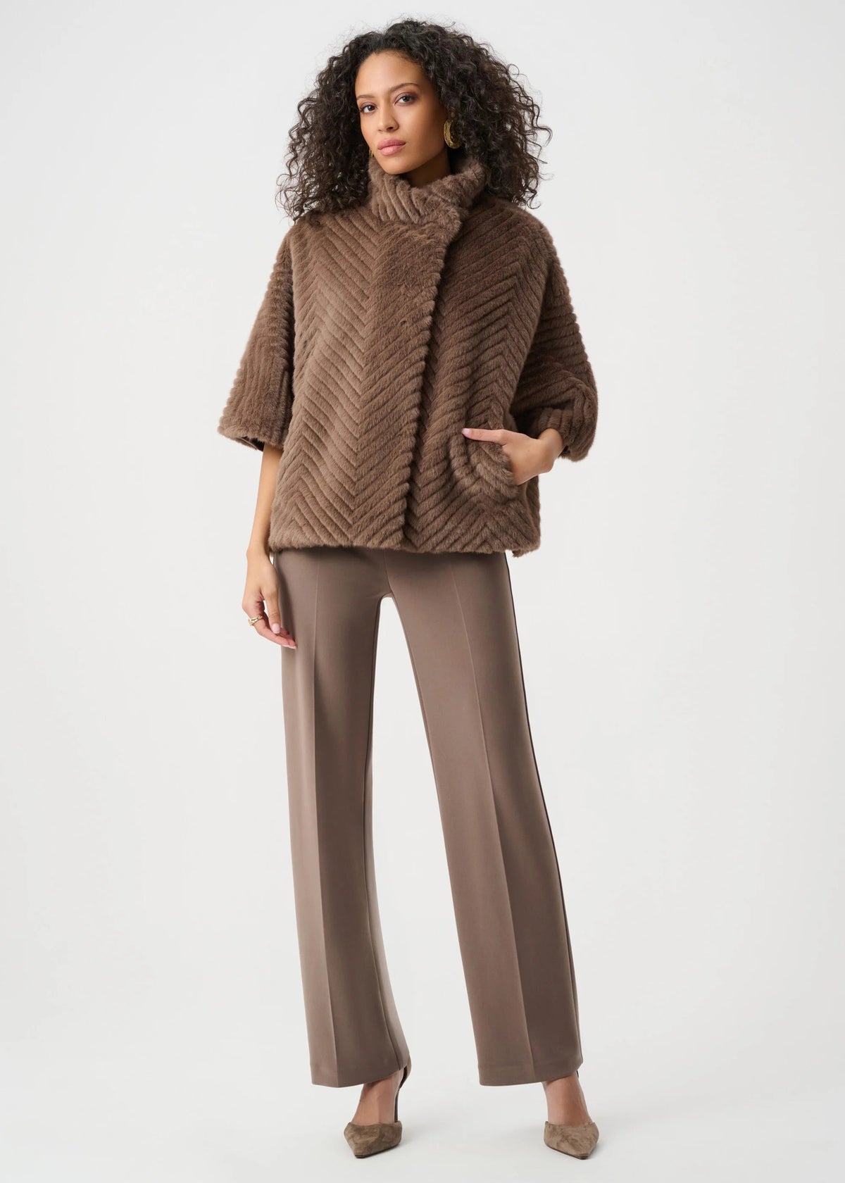 Woman wearing a brown textured sweater and pants on a white background