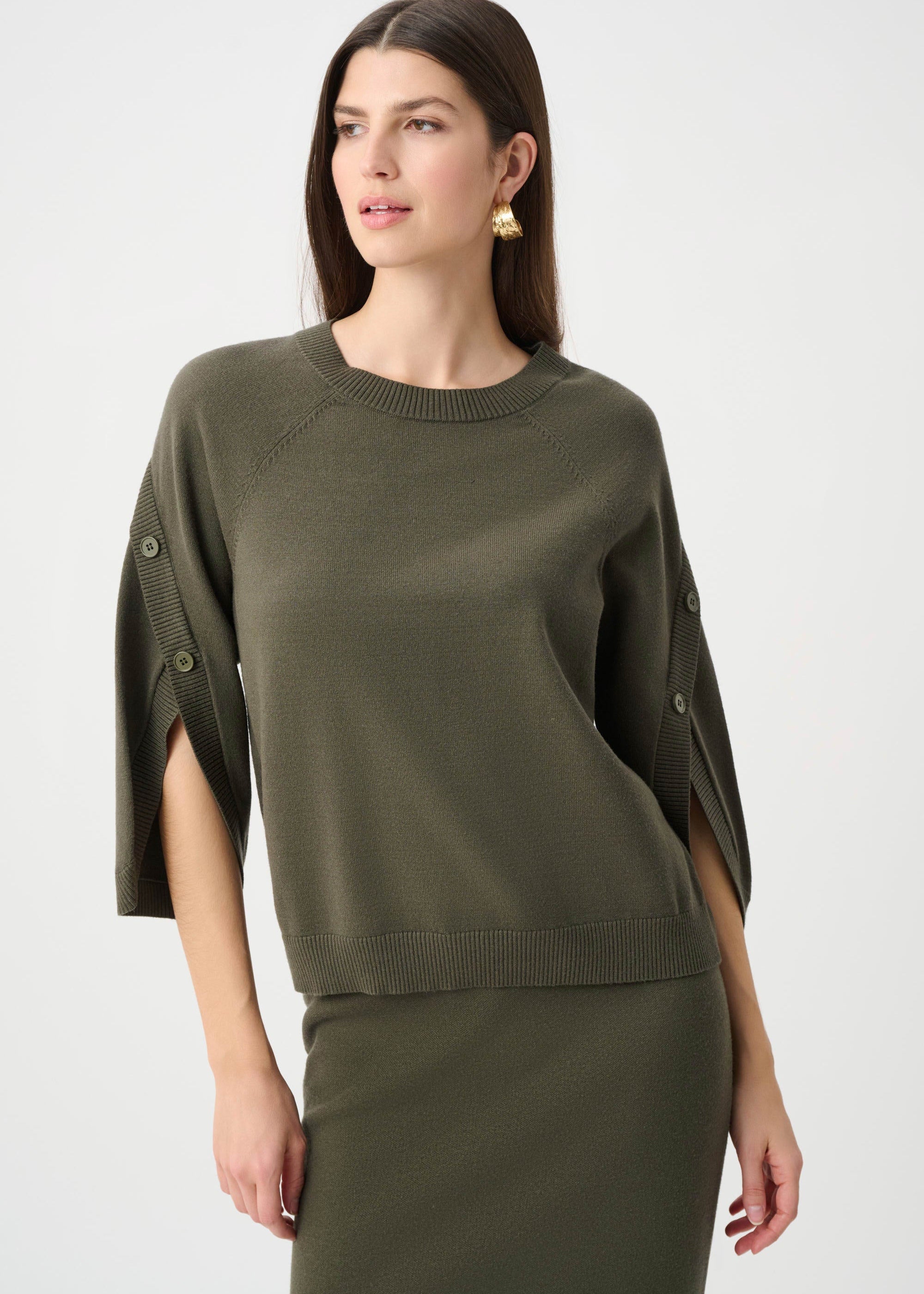 Woman wearing an olive green sweater with cut-out sleeves on a white background