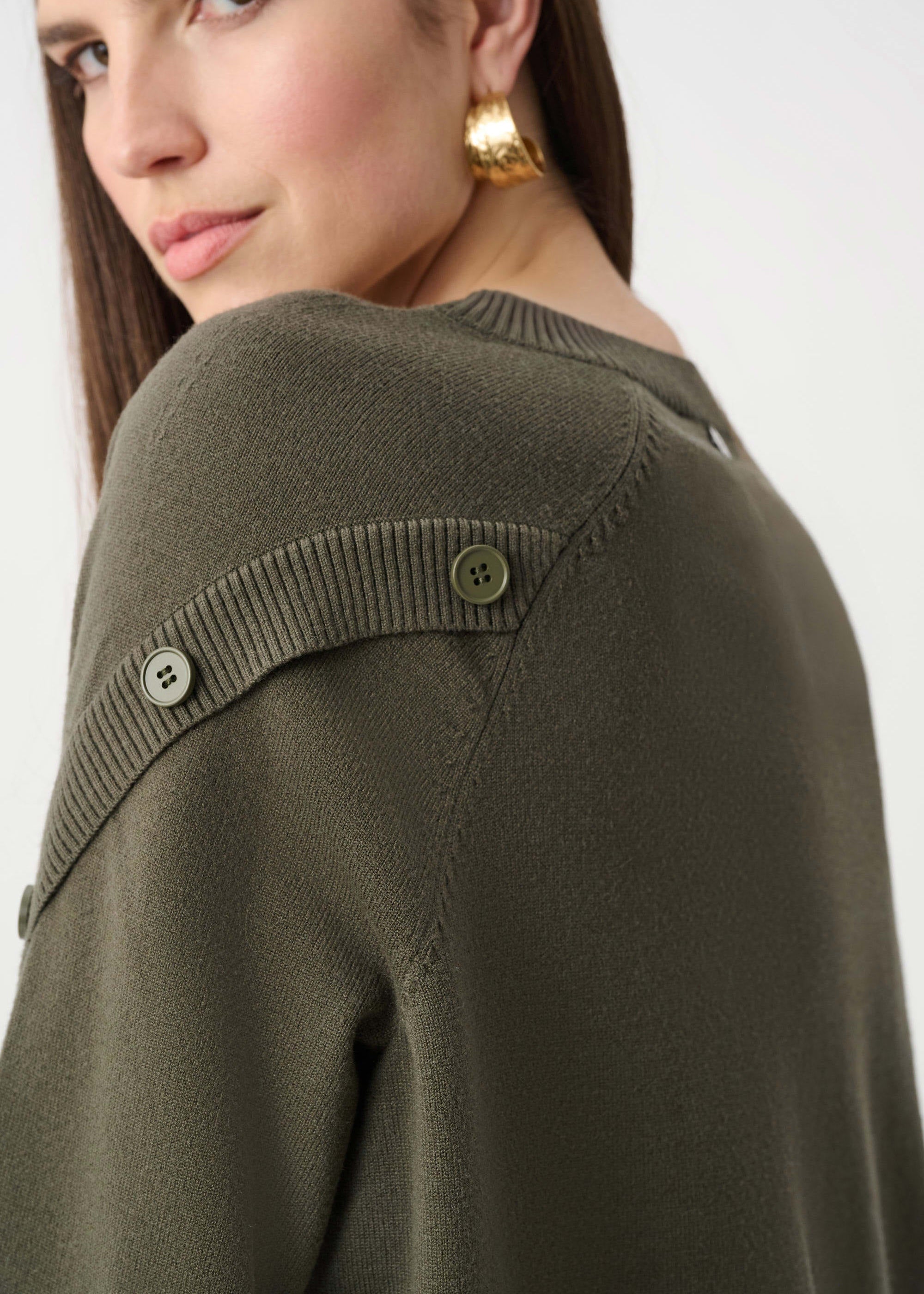 Woman wearing a green sweater with button details on a white background