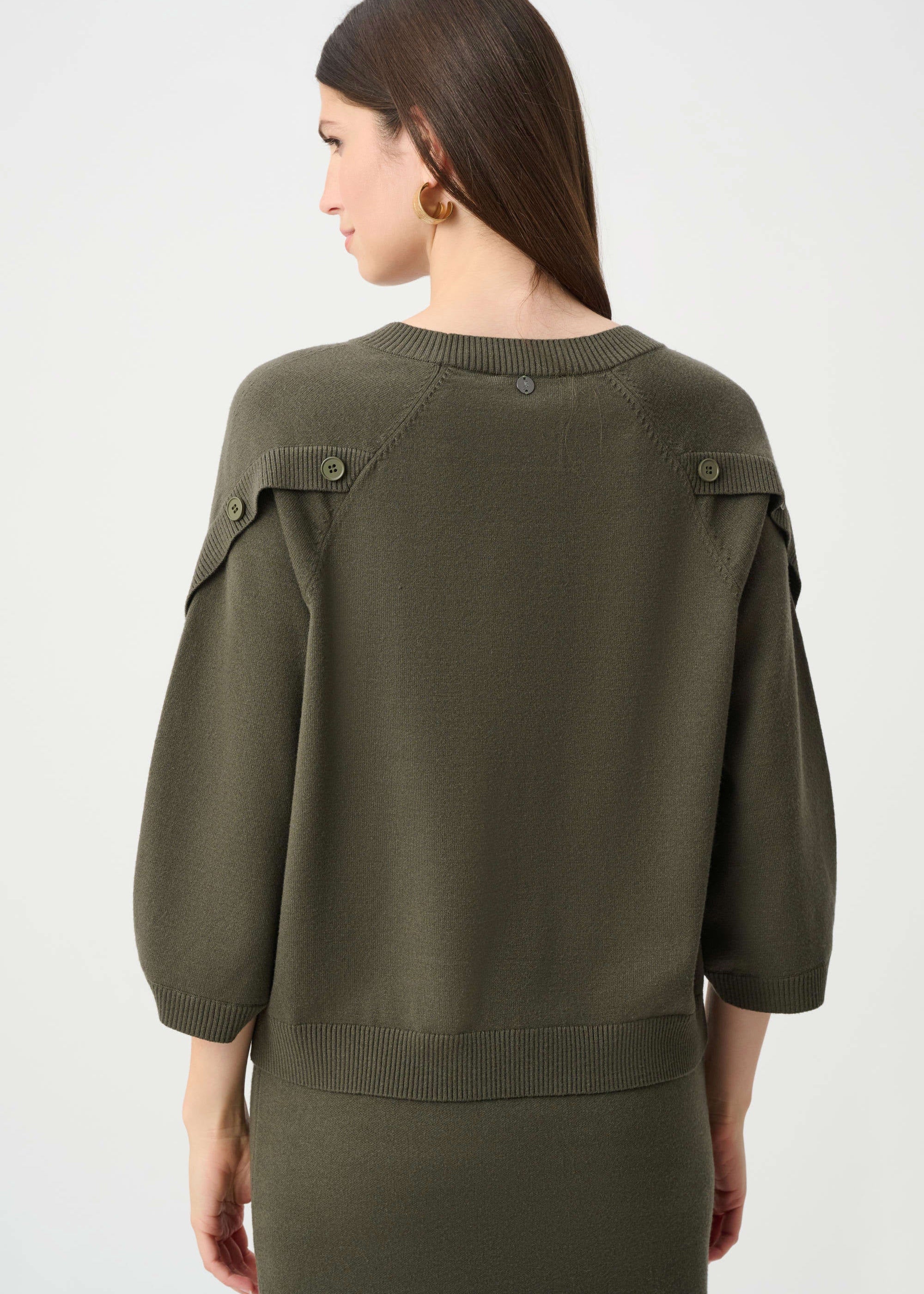 Woman wearing an olive green sweater on a white background