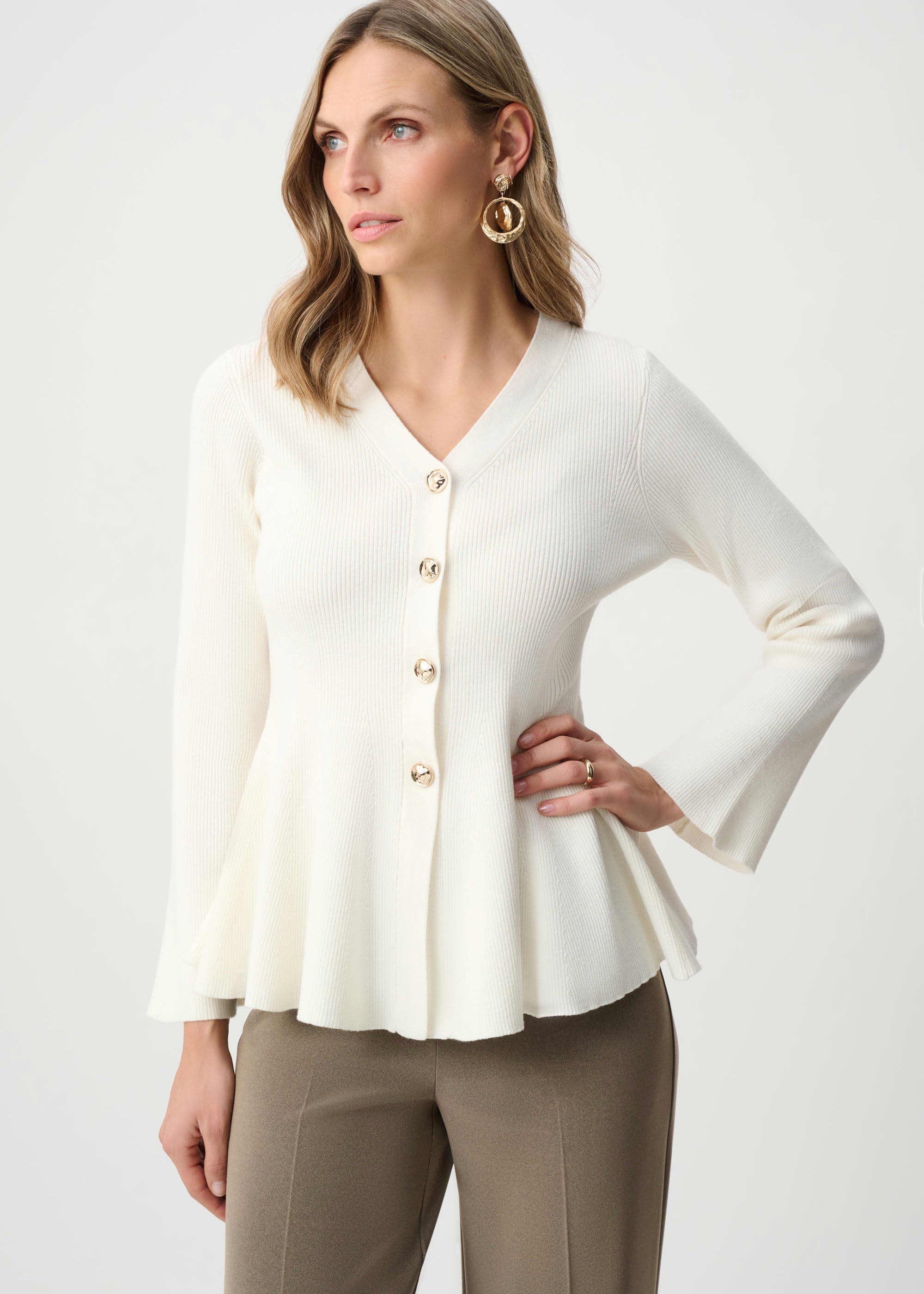 Woman wearing a white blouse with bell sleeves on a plain background