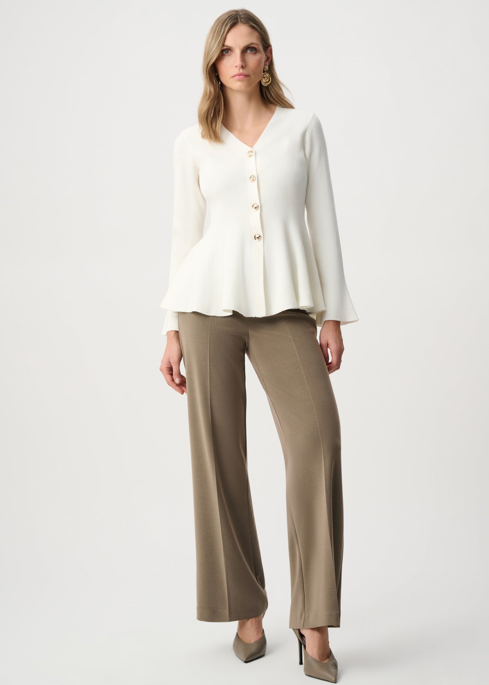 Woman wearing a white blouse and beige pants on a white background