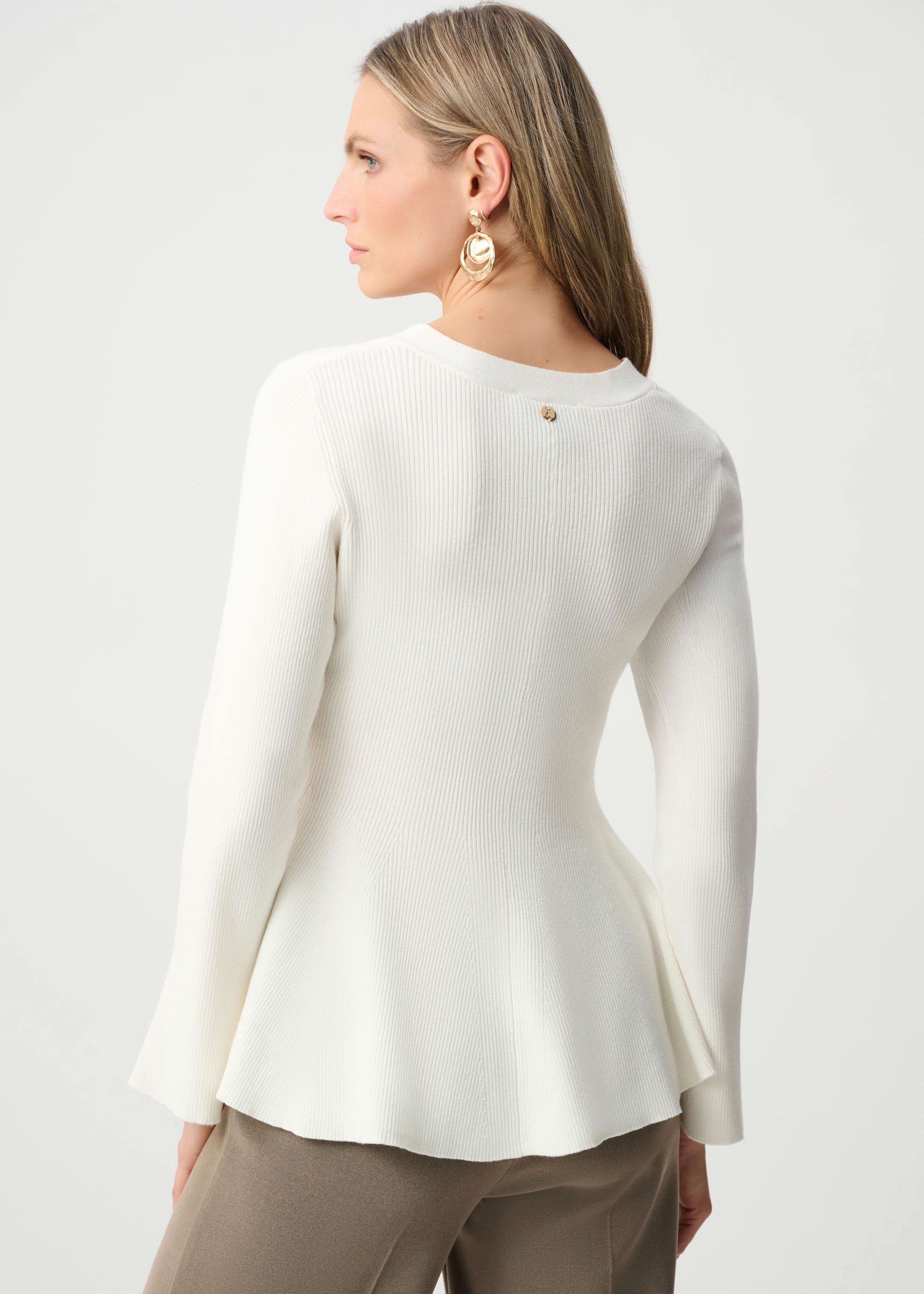 Woman wearing a white blouse and beige pants on a white background