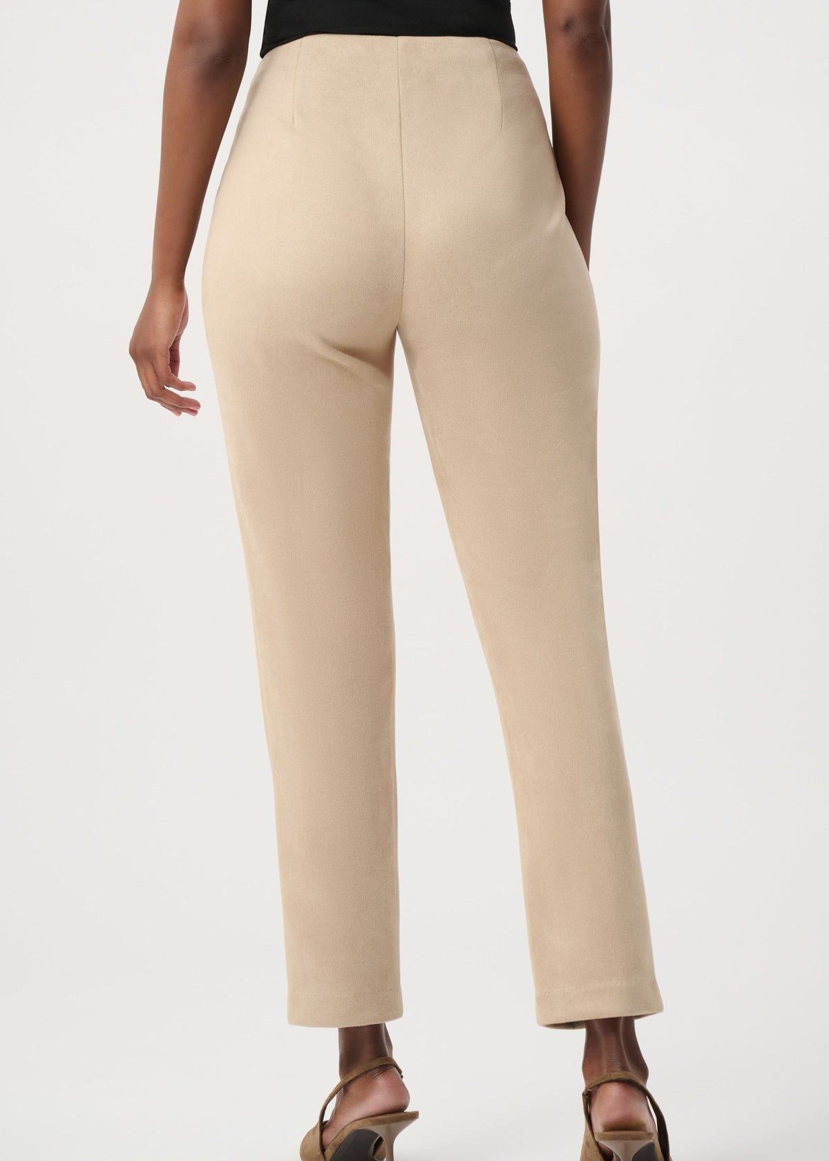 A person shown from the back wearing straight-leg cropped trousers in a light beige or cream tone, paired with brown heeled sandals against a plain light gray studio background.