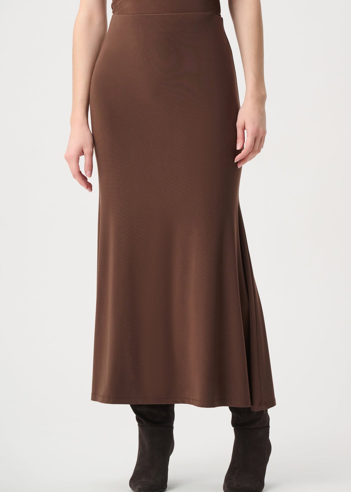 A woman wearing a brown high-waisted midi skirt with a side slit and dark brown ankle boots, shown from the waist down against a light gray studio background.