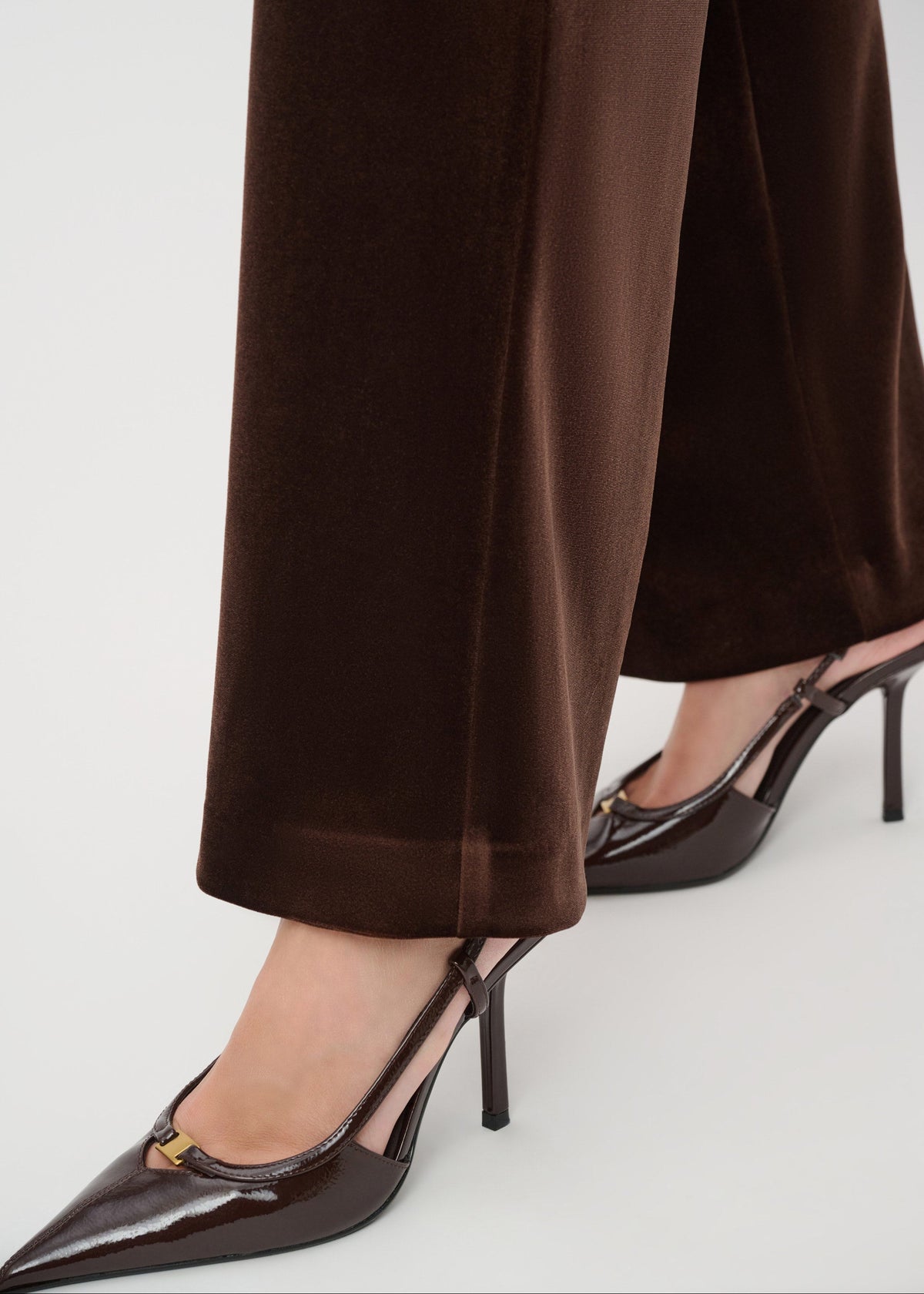 Brown high-waisted pants and black high-heeled shoes on a white background