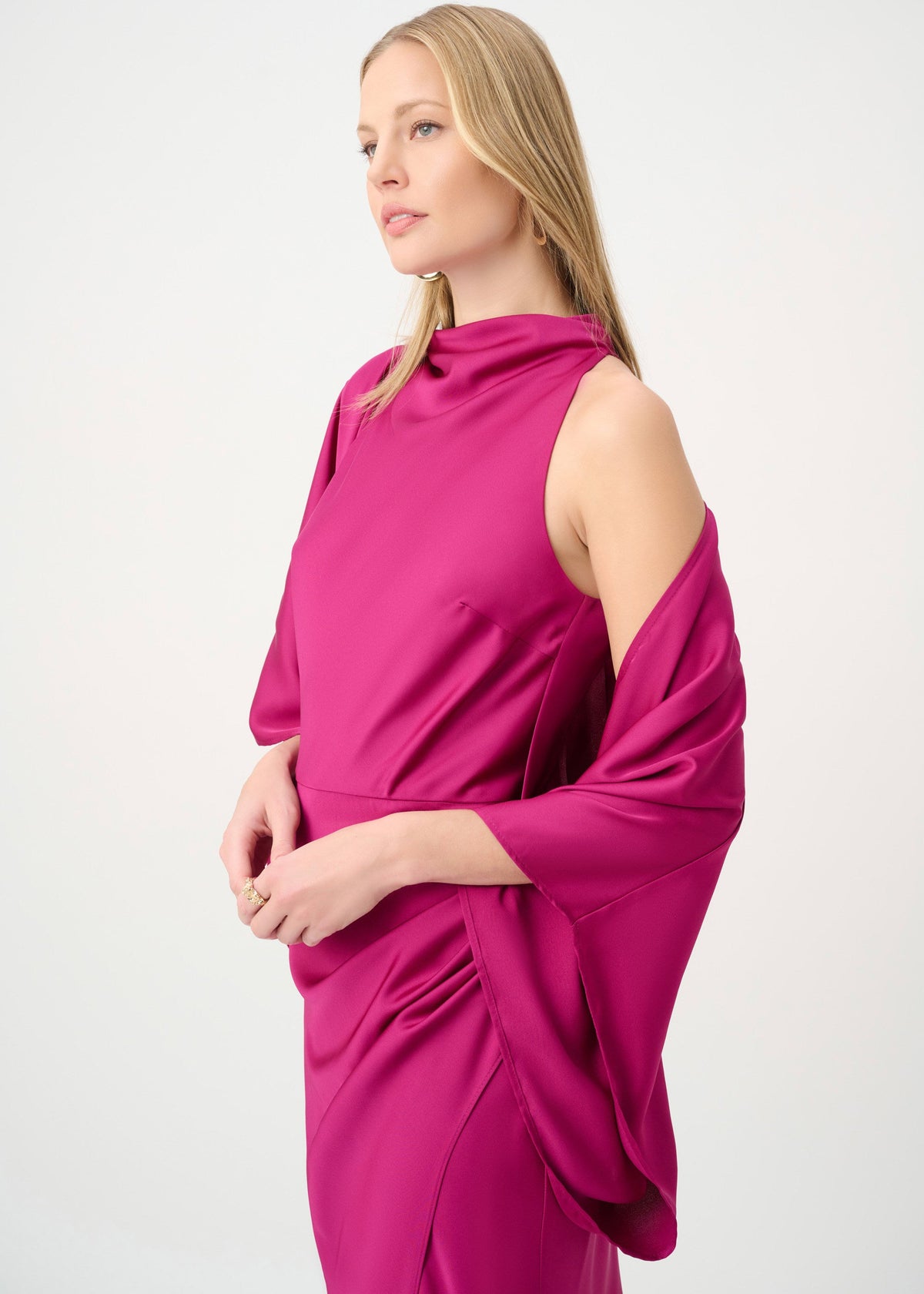 Woman wearing a bright pink dress with cut-out shoulders on a white background