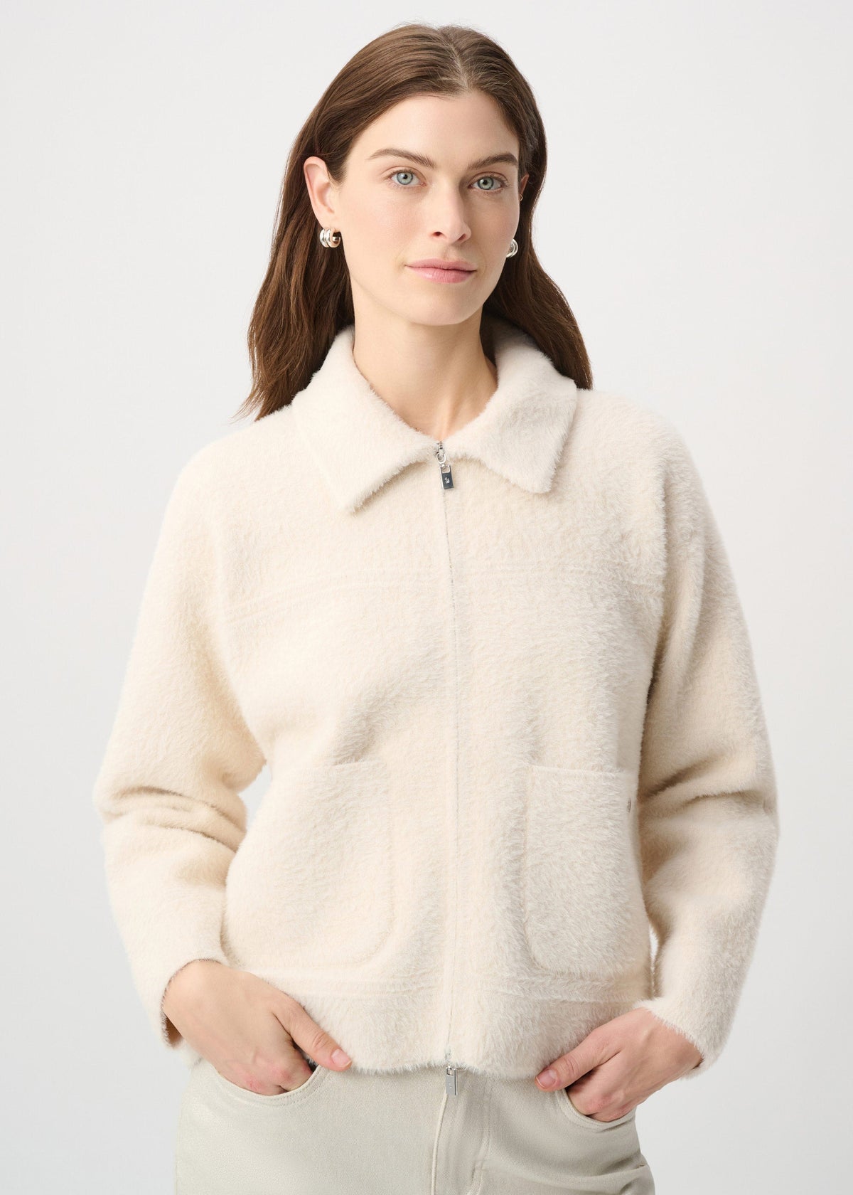 Woman wearing a cream-colored fleece jacket against a plain background
