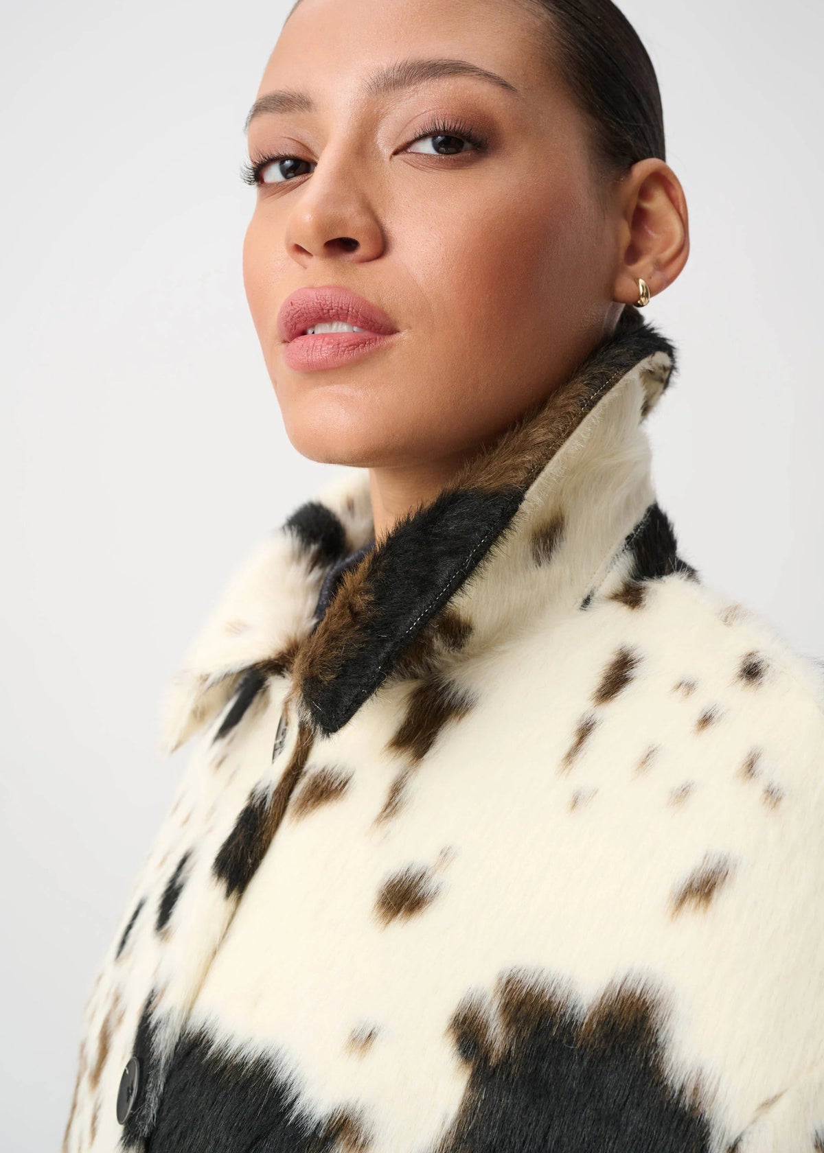 Woman wearing a black and white patterned coat against a plain background