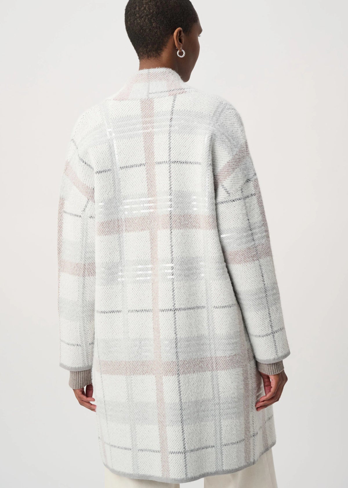 A model shown from the back wearing a long-sleeve, mid-length plaid coat in white, light gray, and soft pink. The coat features a textured knit pattern with intersecting vertical and horizontal plaid lines.
