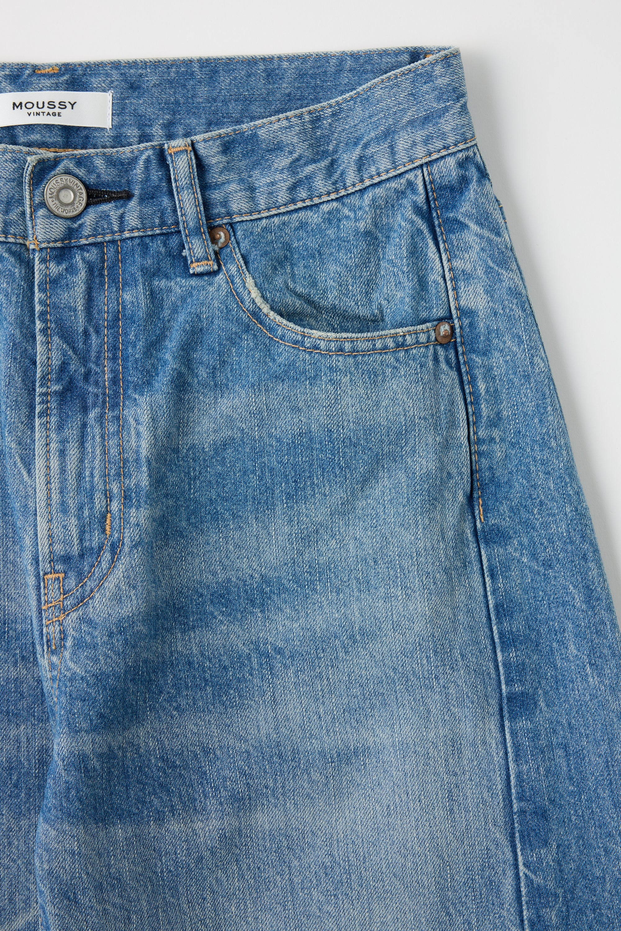 Close-up of Moussy Vintage Bayard Side Line Cocoon Blue jeans with a visible brand label on a white background