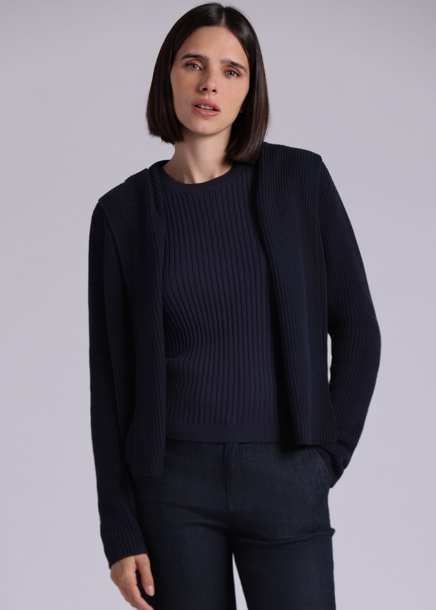 Woman wearing a dark blue outfit against a light gray background