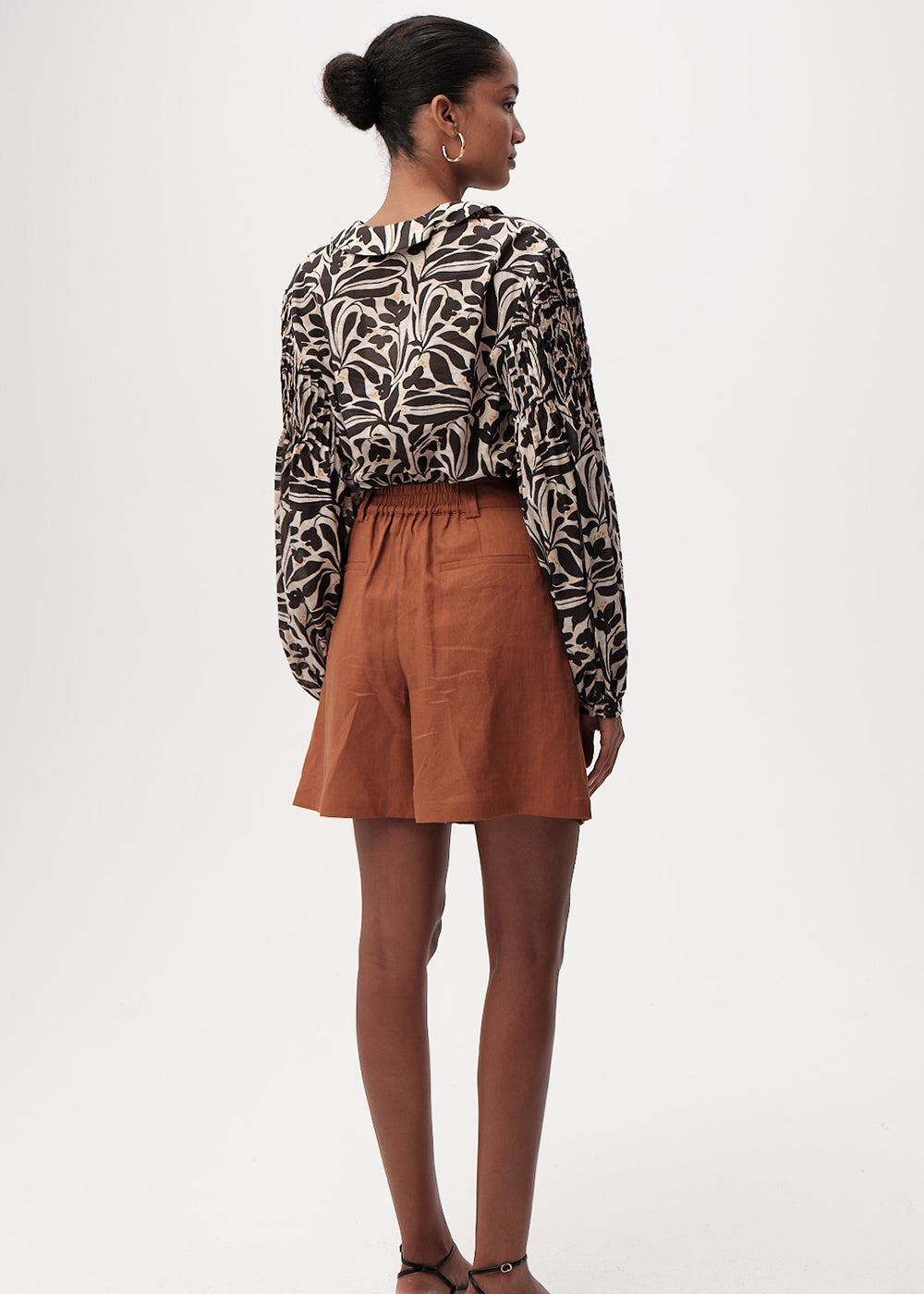Woman wearing a patterned blouse and brown skirt on a white background