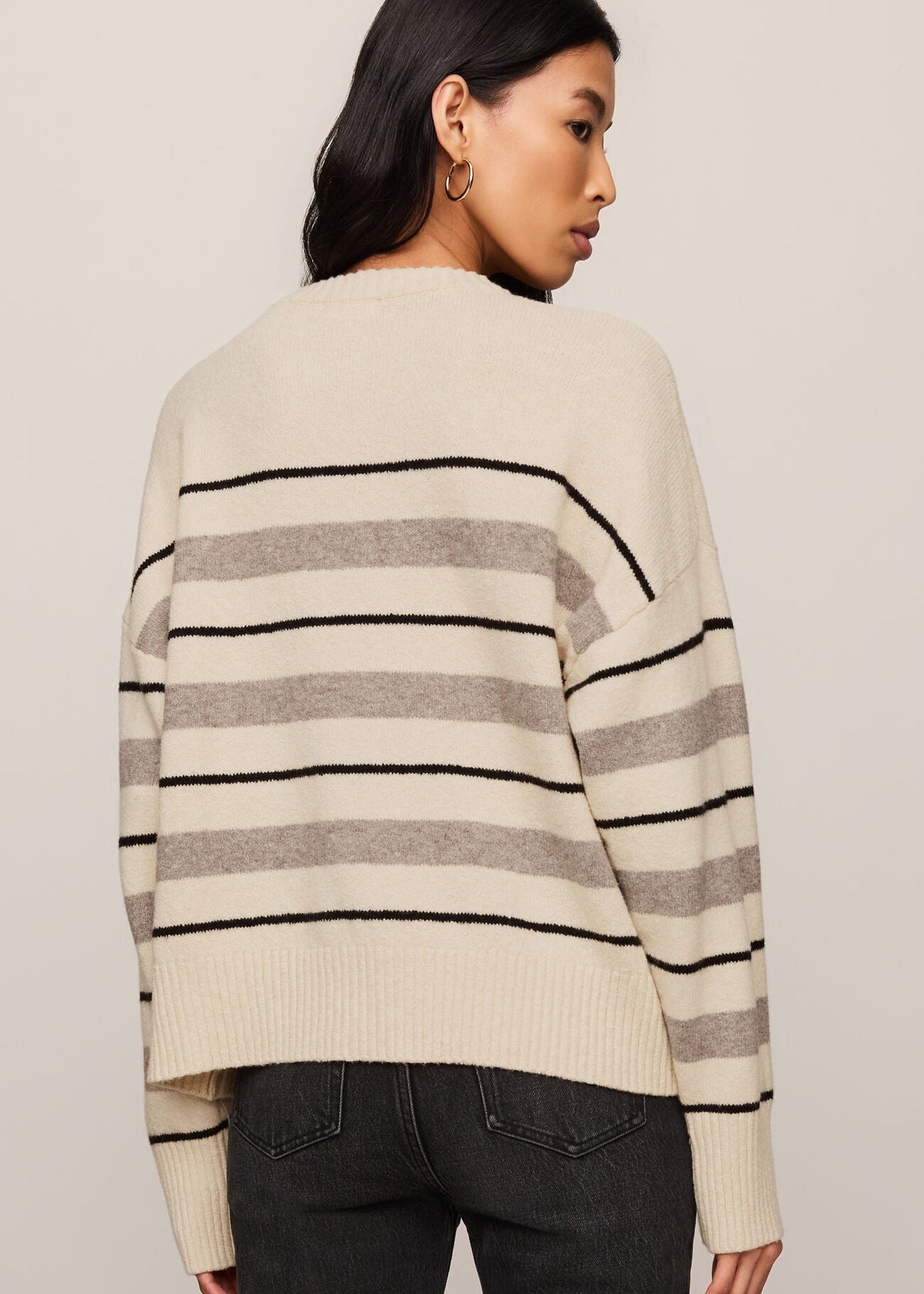 Woman wearing a striped sweater with a neutral background
