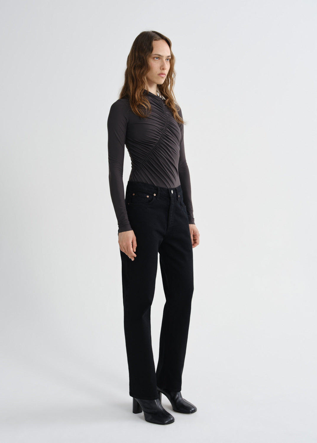 Person wearing a black long-sleeve top and black pants on a white background