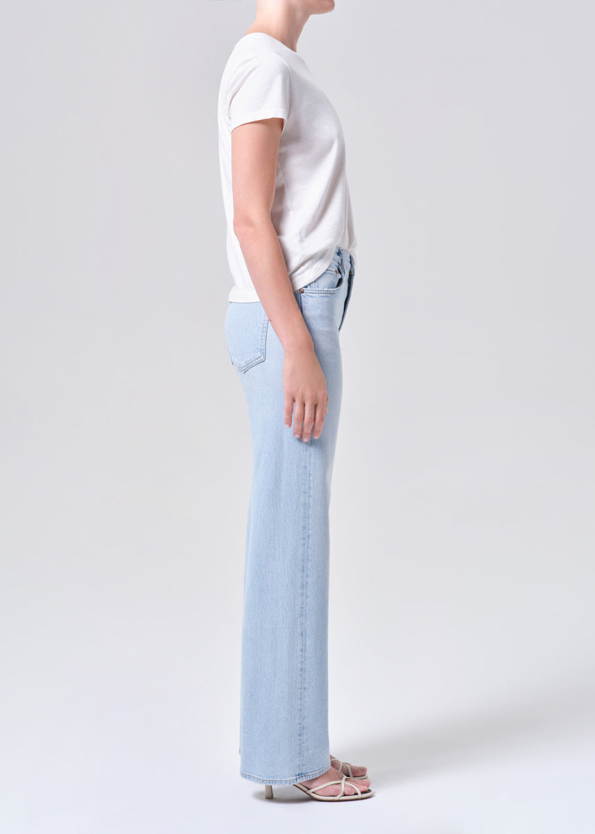 Person wearing a white t-shirt and light blue jeans on a plain background