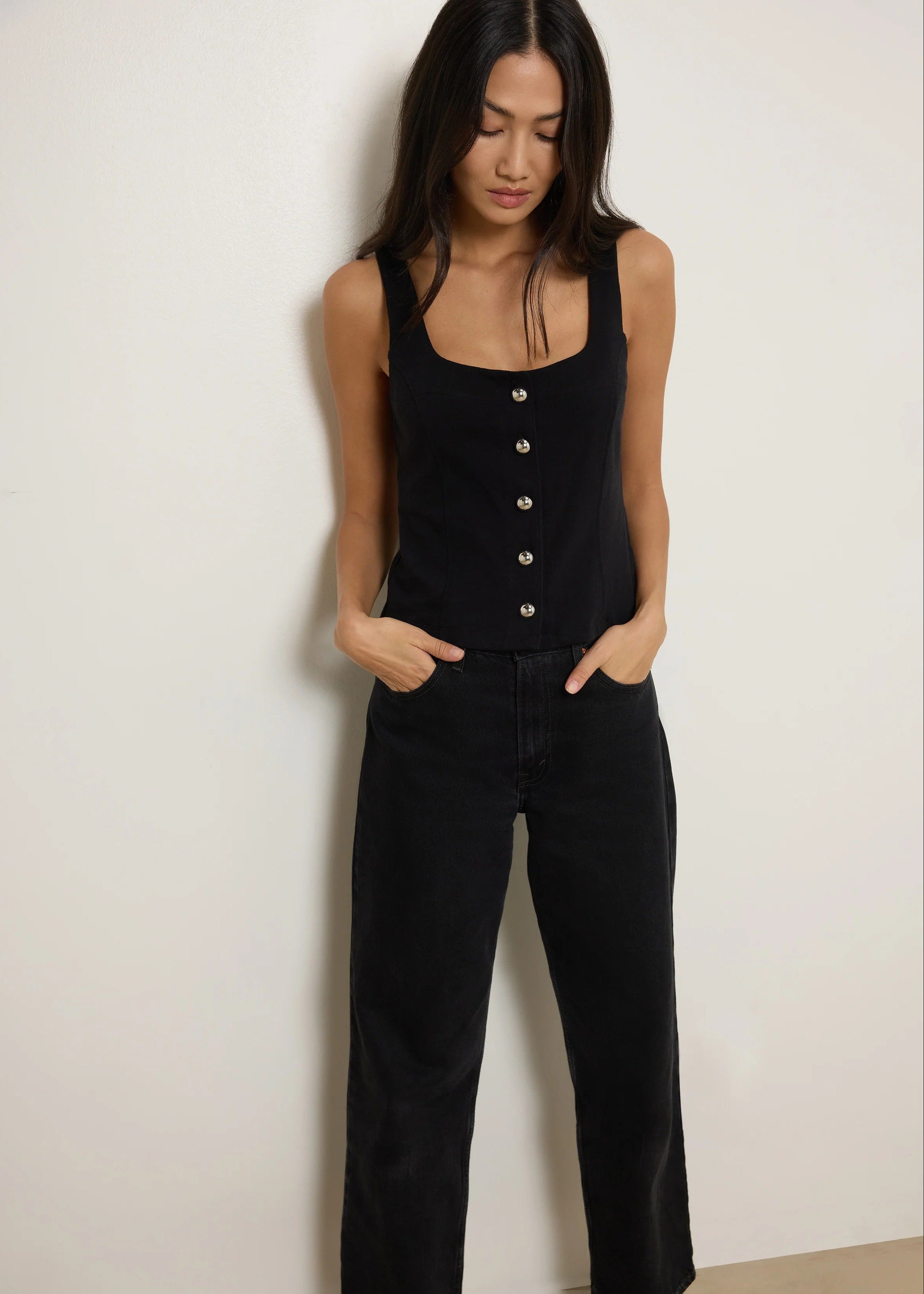 Woman wearing a black sleeveless top and black pants against a white background