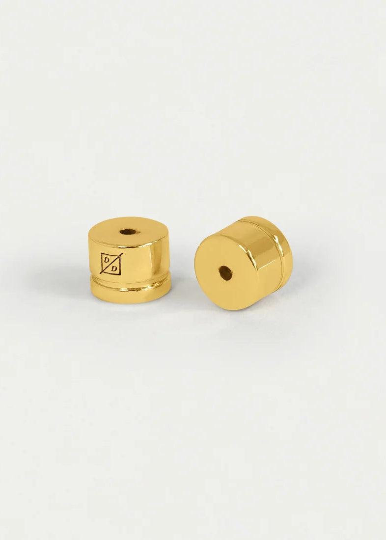 Two small gold metallic cylindrical hardware pieces with threaded ends and center holes, shown on a clean white background.