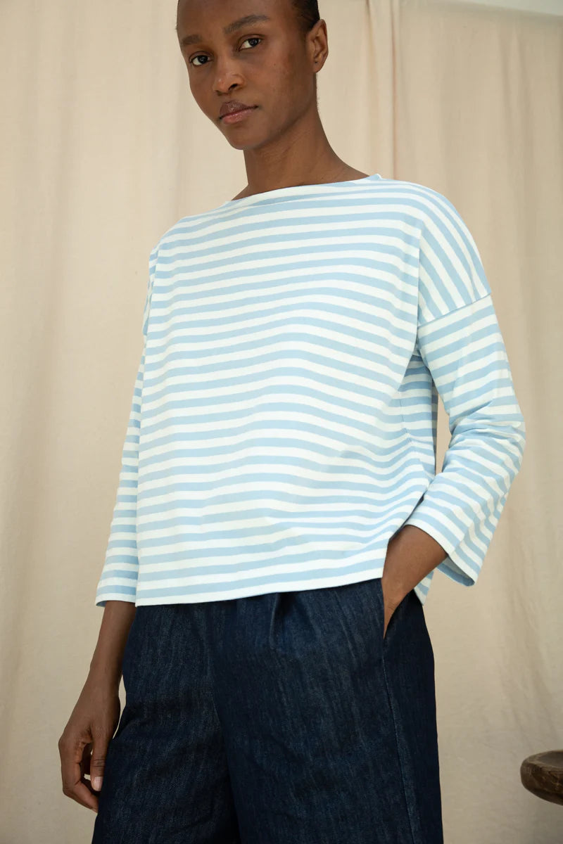 Person wearing a light blue and white striped long-sleeve shirt against a neutral background