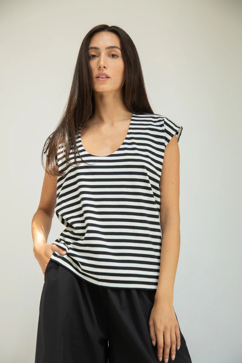 Woman wearing a black and white striped sleeveless top against a plain background