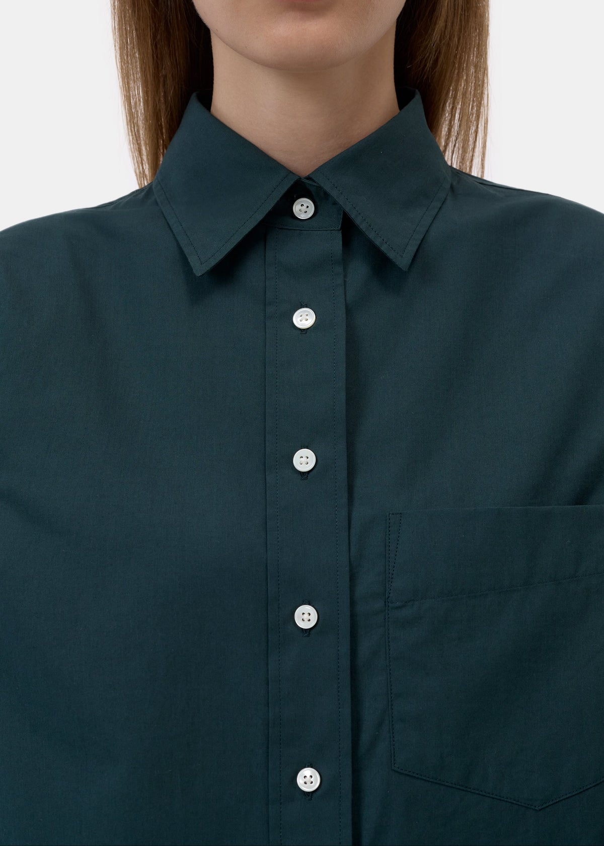 Close-up of a model wearing a dark teal-green button-down shirt with a pointed collar and white buttons.