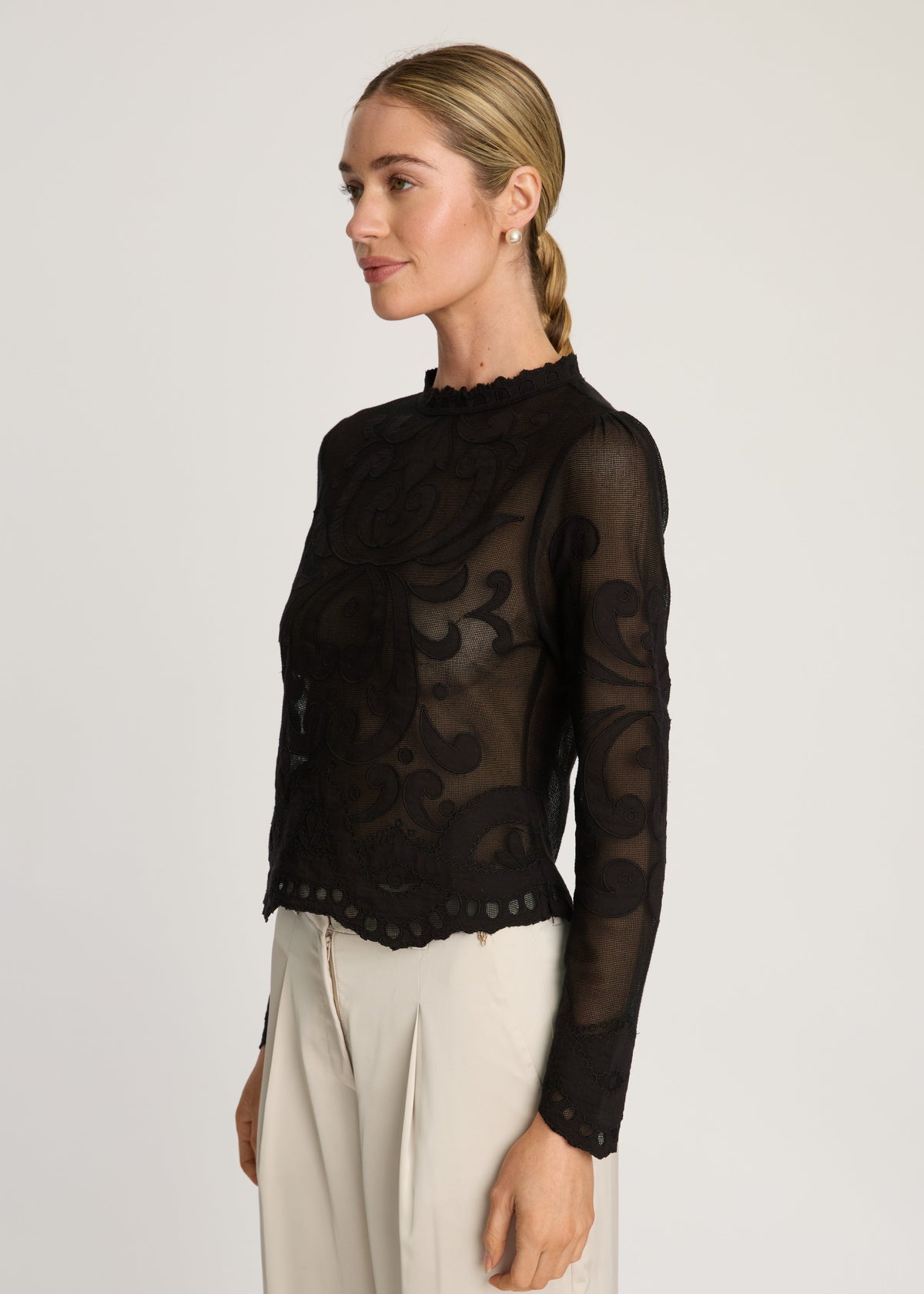 Woman wearing a black sheer top with long sleeves on a white background
