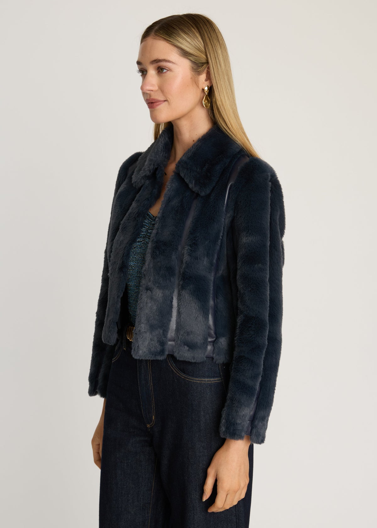 Woman wearing a dark blue fur jacket on a plain background
