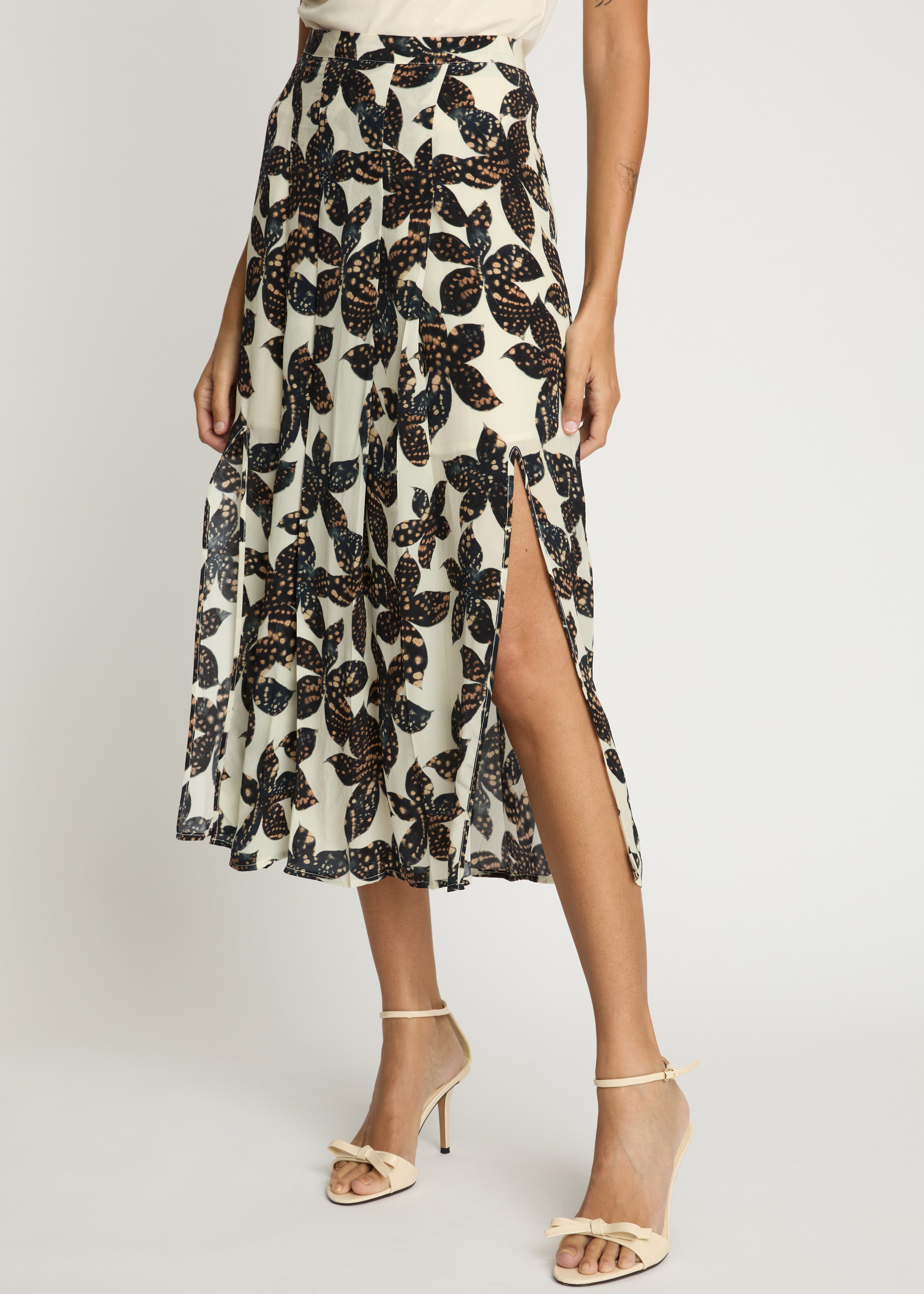 Person wearing a floral patterned skirt with a slit on a white background