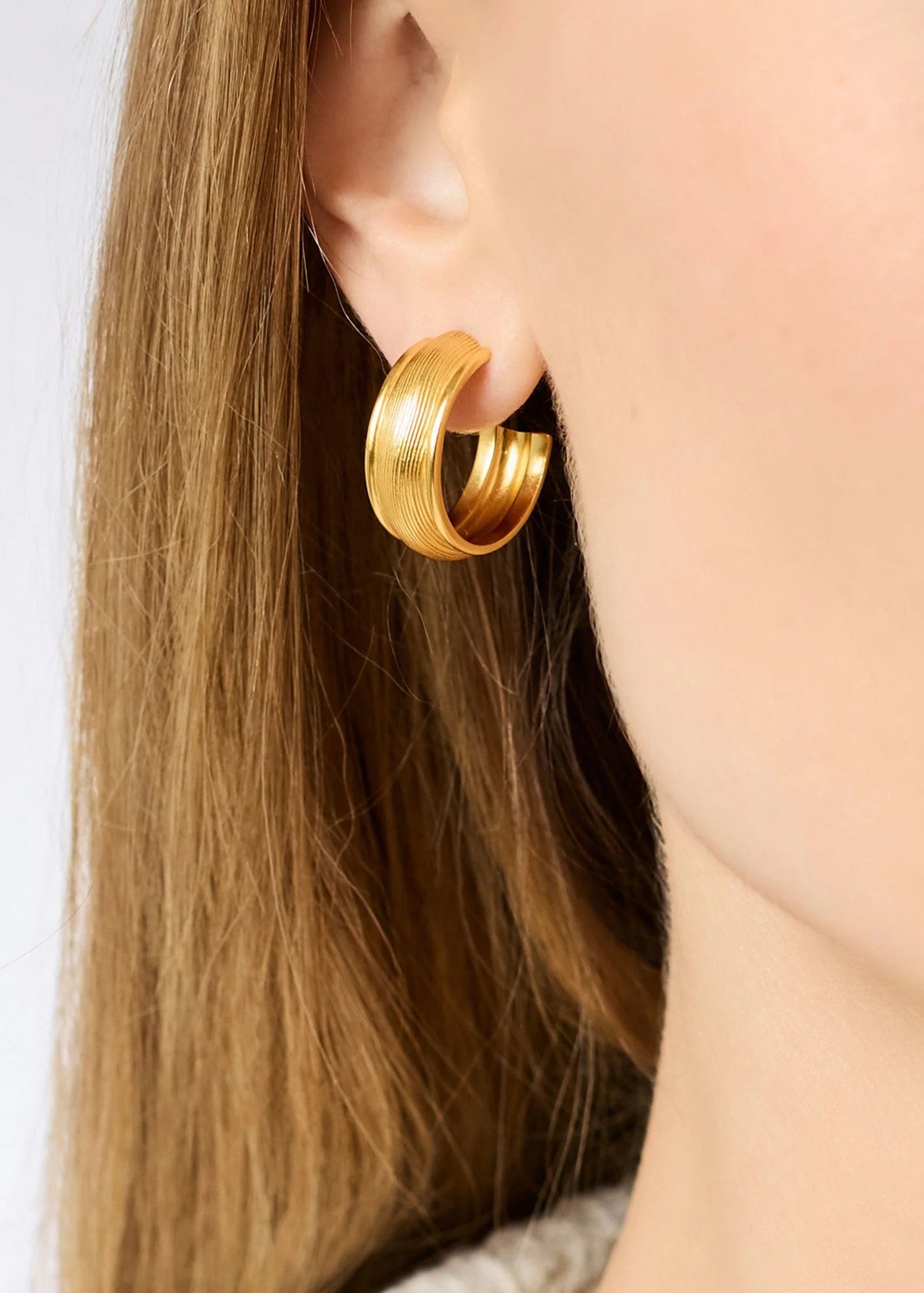 woman wearing gold plated hoop earings