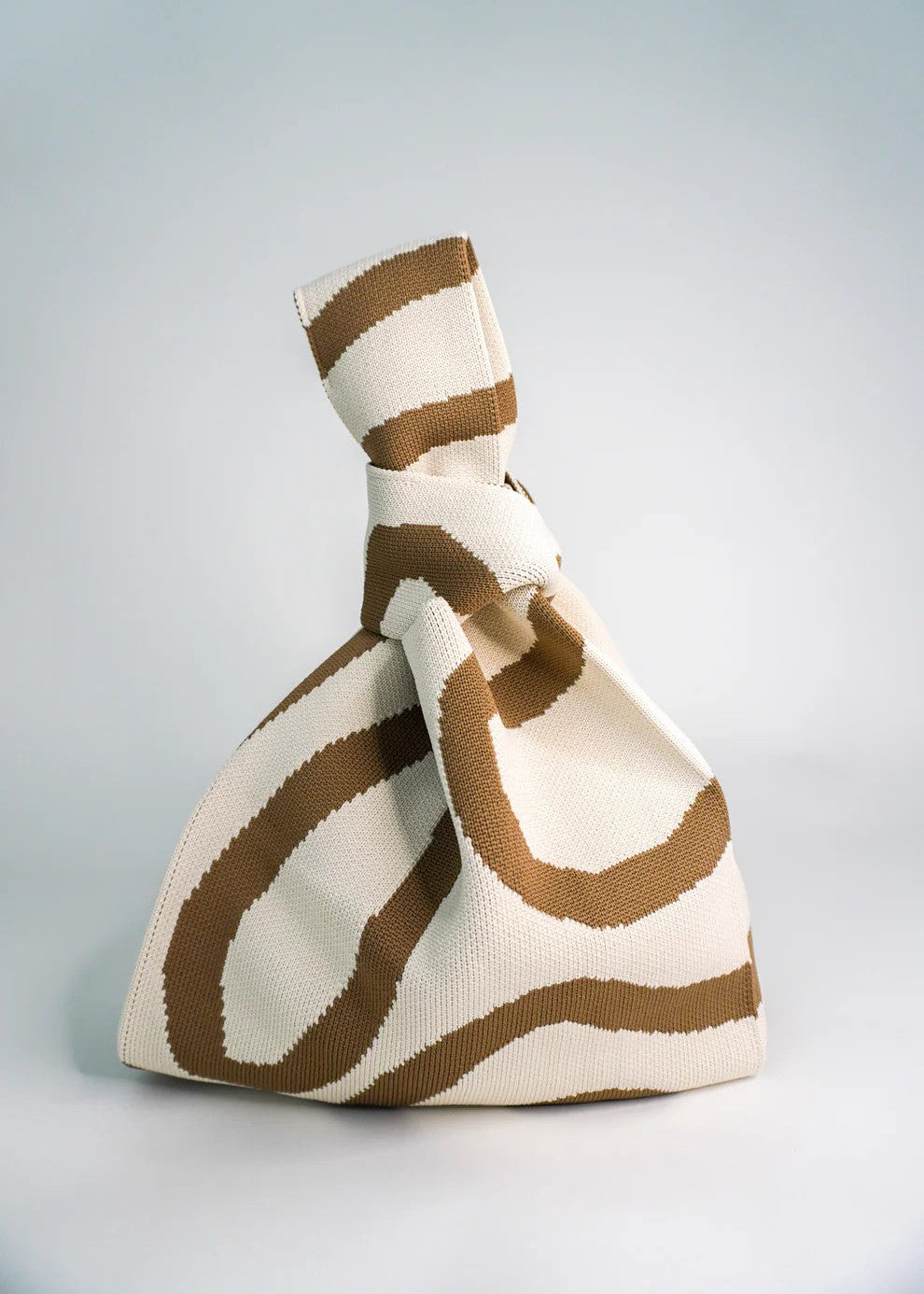 Knitted bag with brown and white pattern on a light gray background