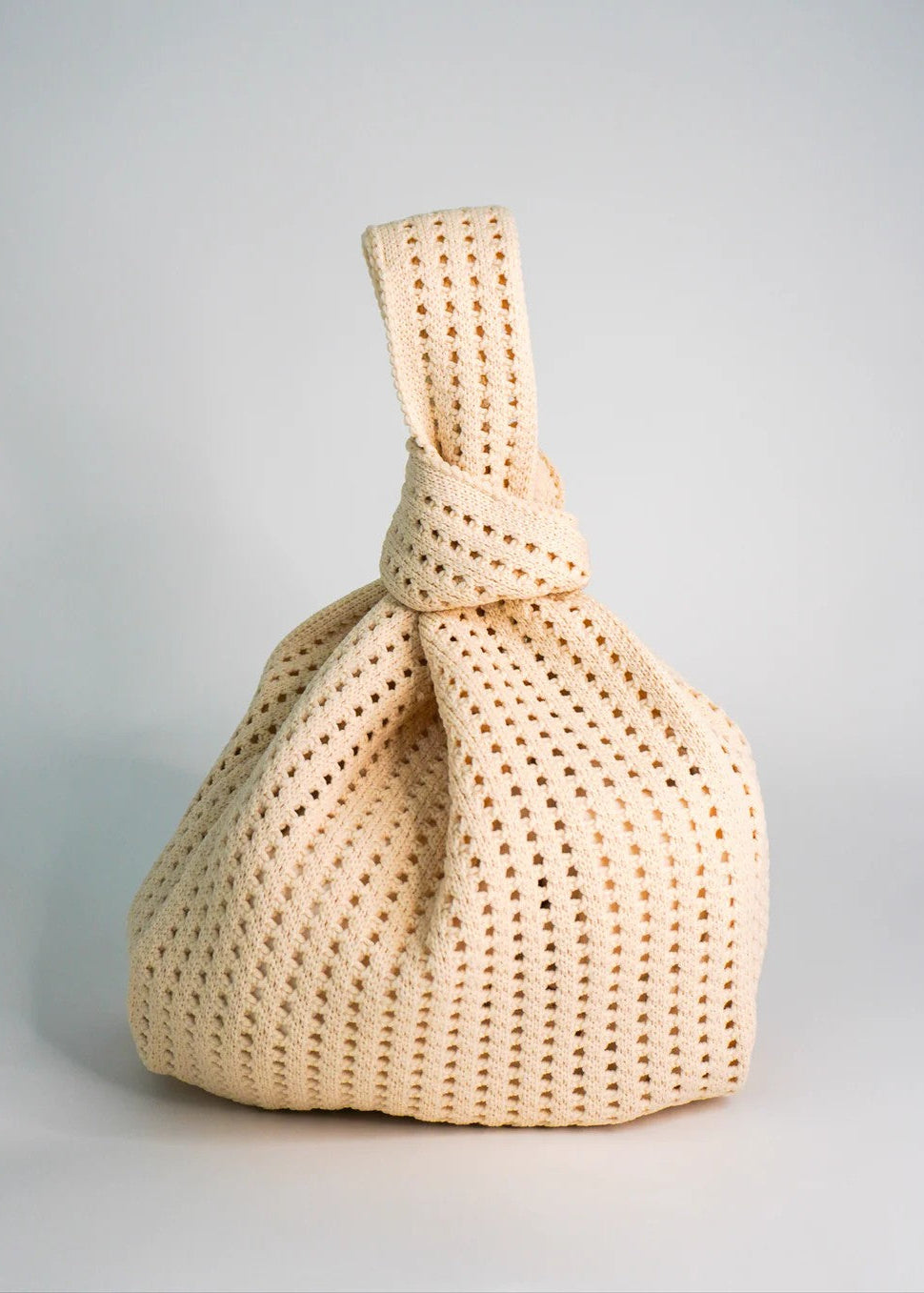 Beige woven handbag on a light gray background