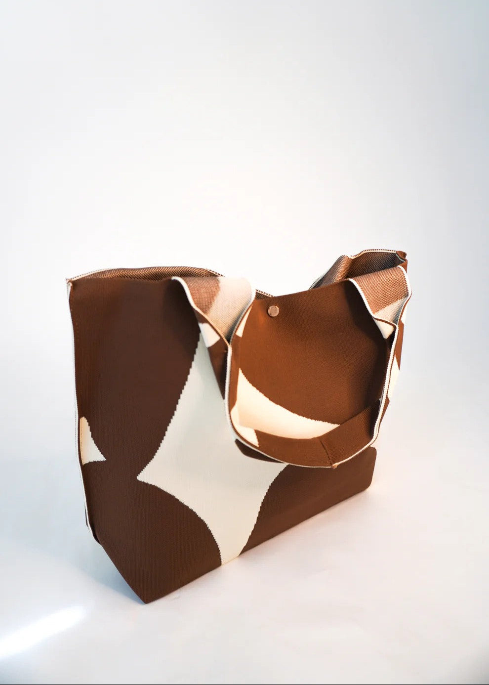 Brown and beige patterned handbag on a white background