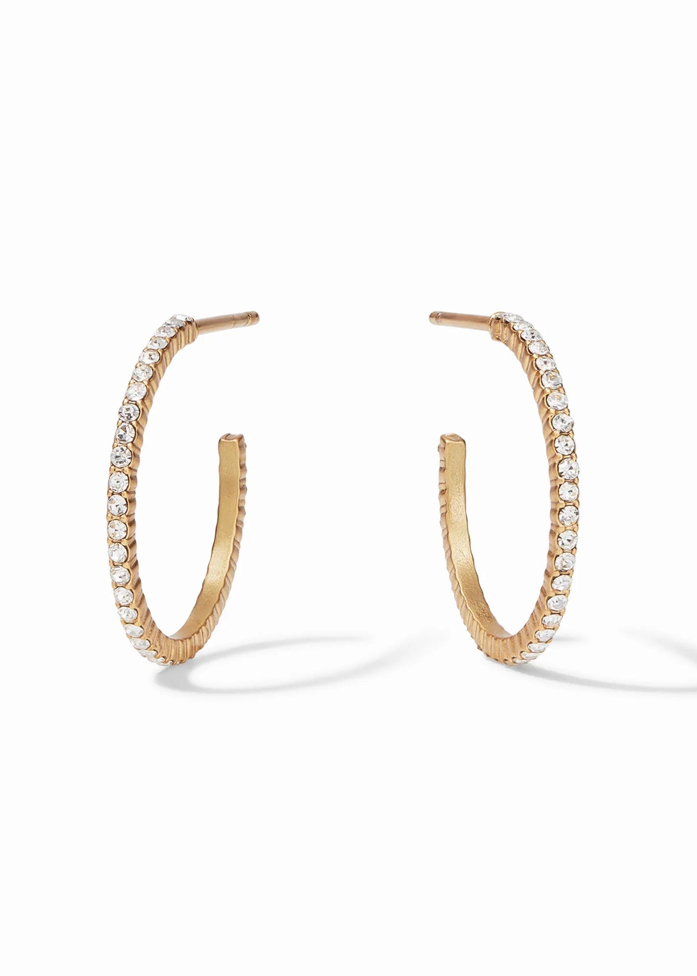 A pair of gold hoop earrings with a row of clear pavé-set stones along the front, shown on a clean white background with soft shadows.