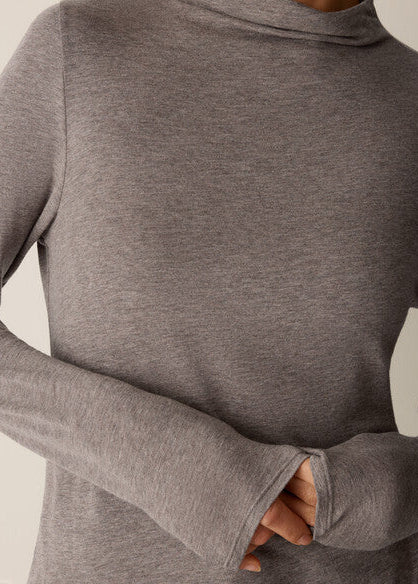 A close-up of a person wearing a heather gray long-sleeve mock neck top, showing the fabric texture and the sleeve cuff detail.