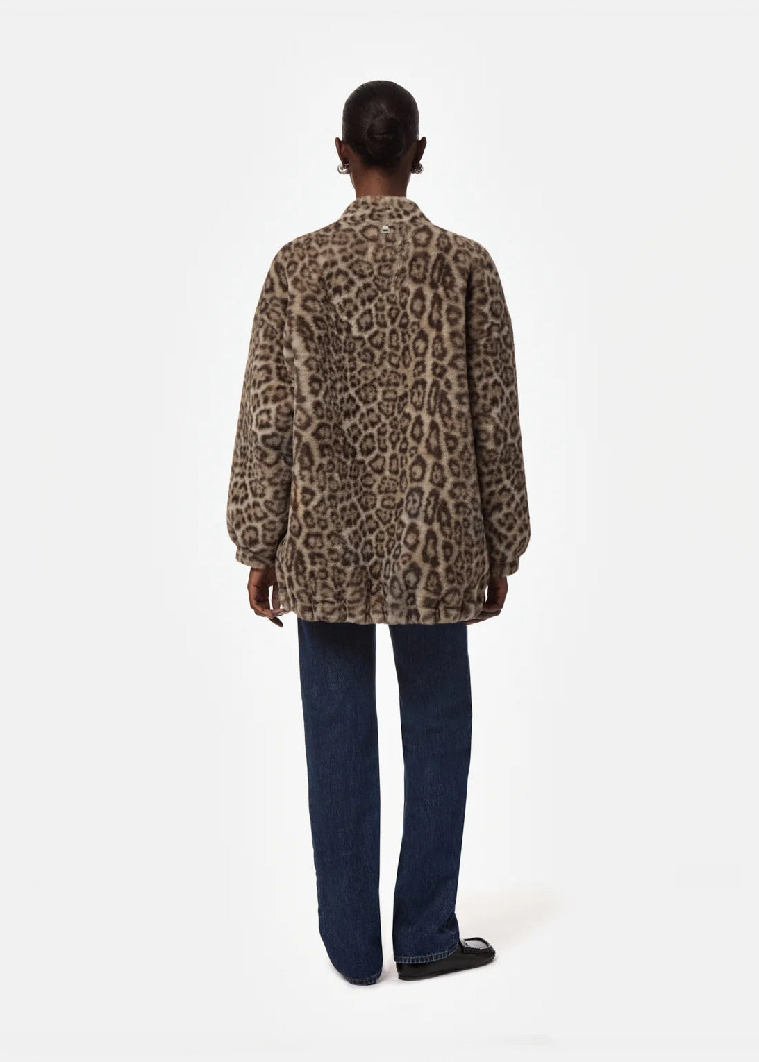 A model shown from the back wearing a brown and black leopard print jacket with dark blue jeans, against a plain white studio background.