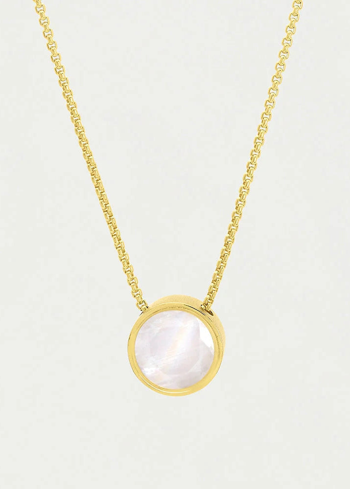 A delicate gold chain necklace featuring a round bezel-set moonstone pendant with a soft pearlescent white and gray sheen, displayed against a clean, light off-white background.