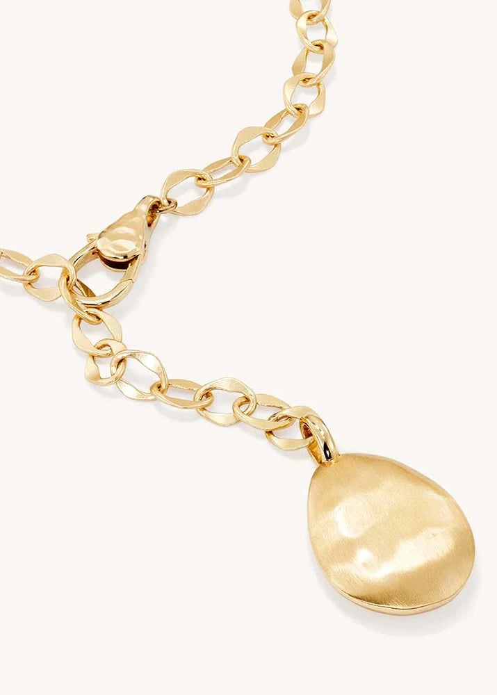 A gold chain necklace featuring a large, hammered-texture teardrop pendant, shown against a clean off-white background.