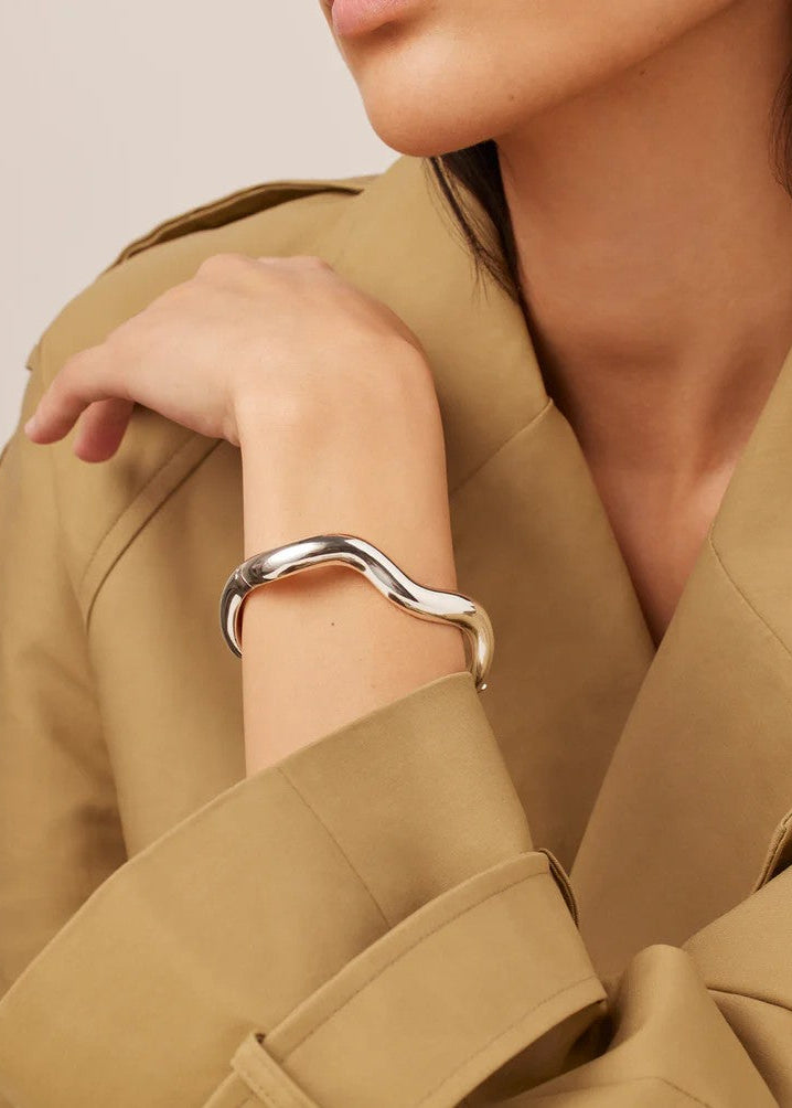 Woman wearing a silver bracelet on a beige background