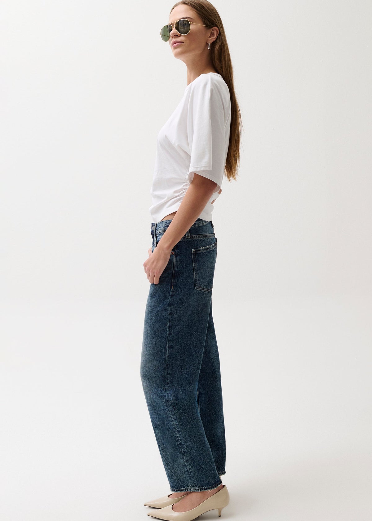 Woman wearing a white t-shirt and blue jeans on a white background